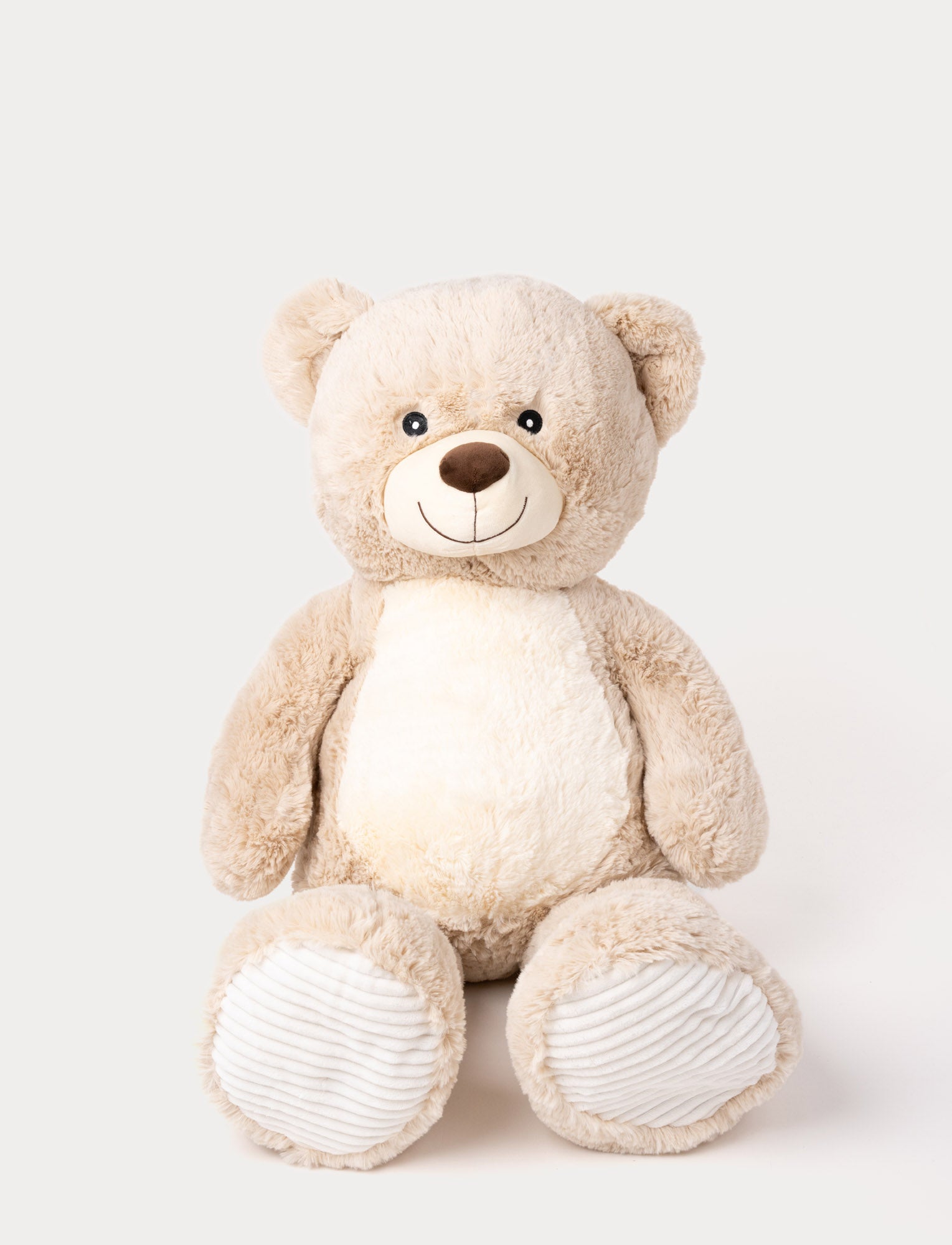 Image of Soft beige teddy bear with a white belly, embroidered smile, and ribbed fabric on its paws.