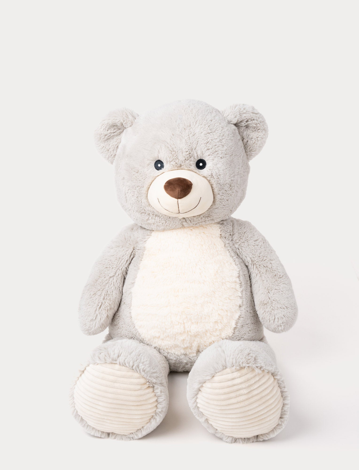 Image of Soft grey teddy bear with a white belly, embroidered smile, and ribbed fabric on its paws.