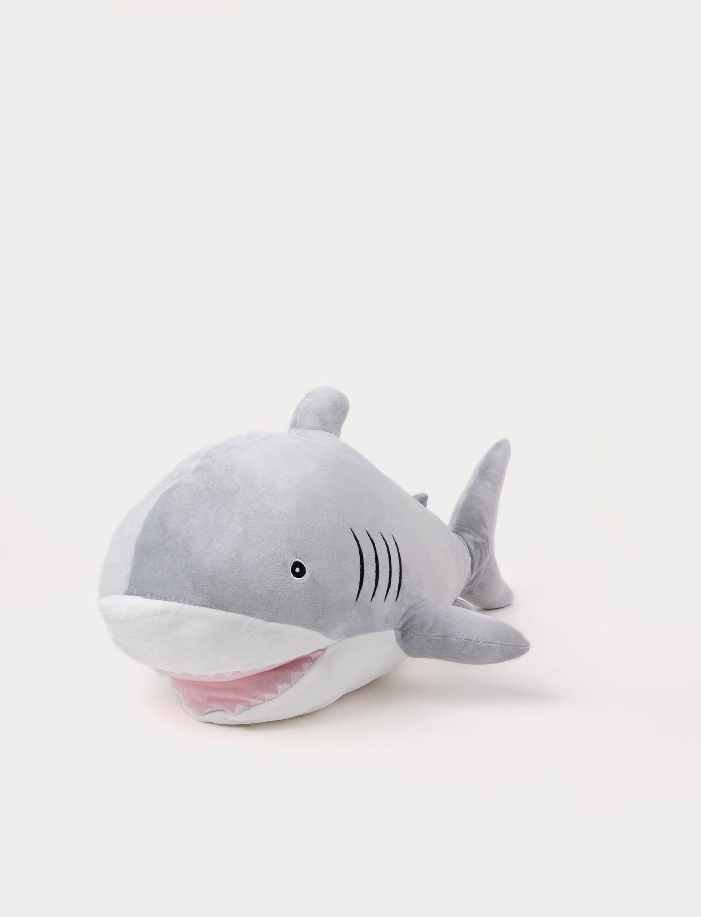Soft plush shark in grey and white with embroidered gills, a friendly smile, and a pink mouth.