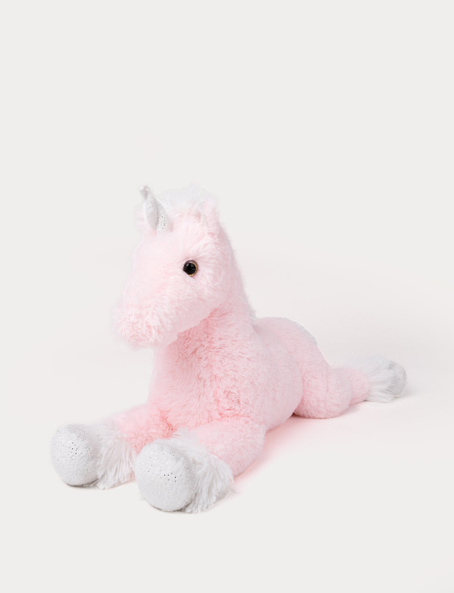 Image of Soft pink unicorn plush toy lying down with sparkly silver horn and hooves.