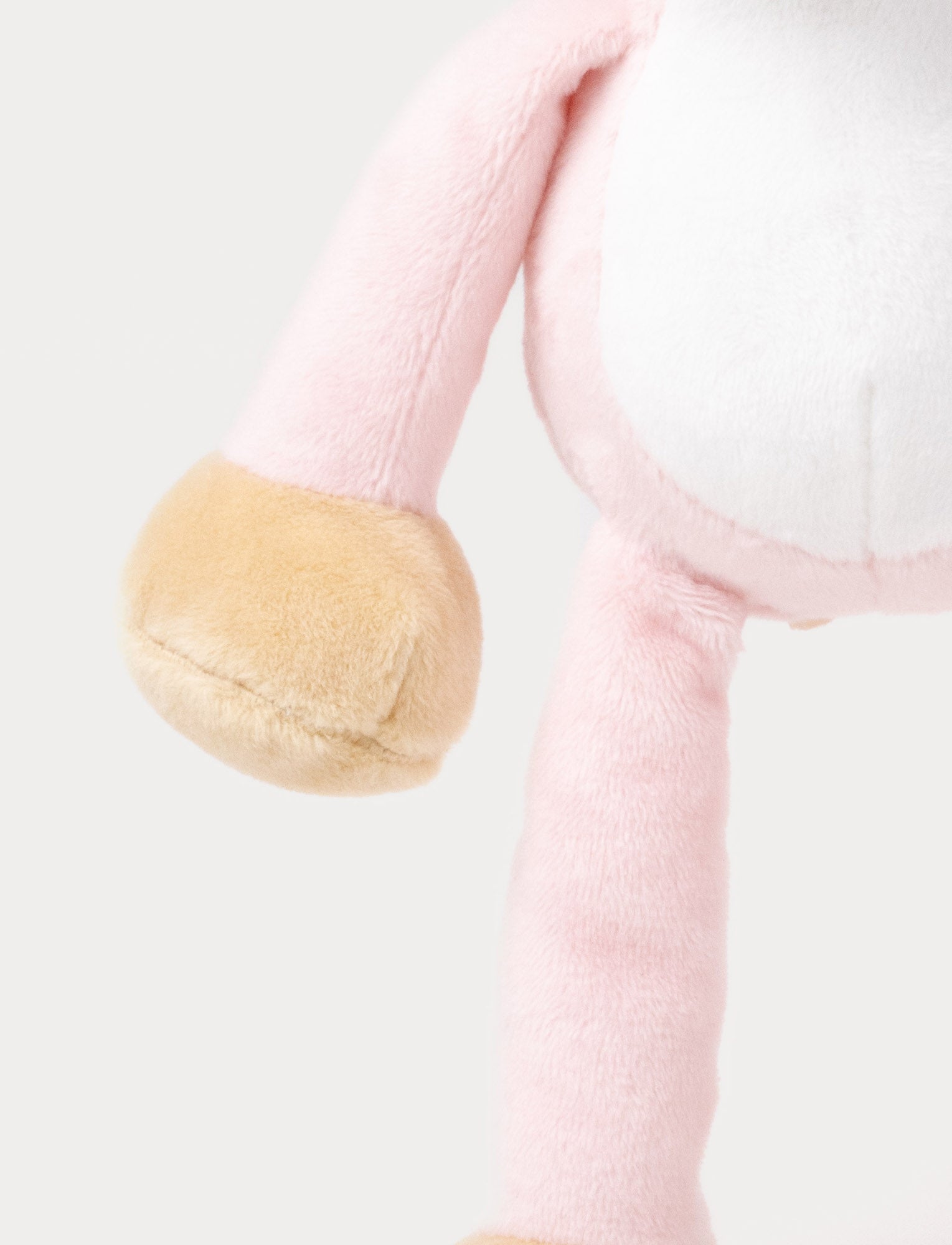 Image of A plush pink cat music box toy with a white belly, beige paws, a stitched smiling face, and a fabric loop on top for hanging