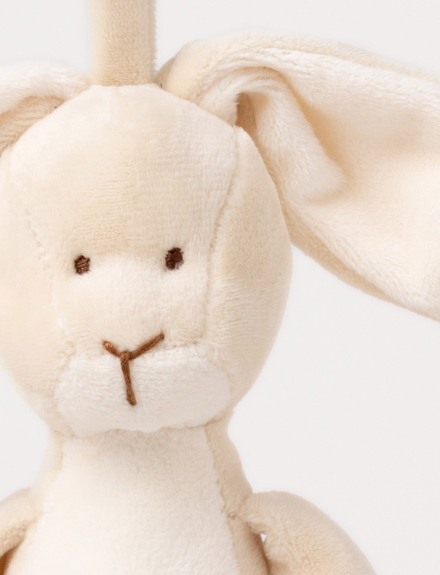 A plush beige bunny music box with floppy ears, a white belly, and a hanging loop.
