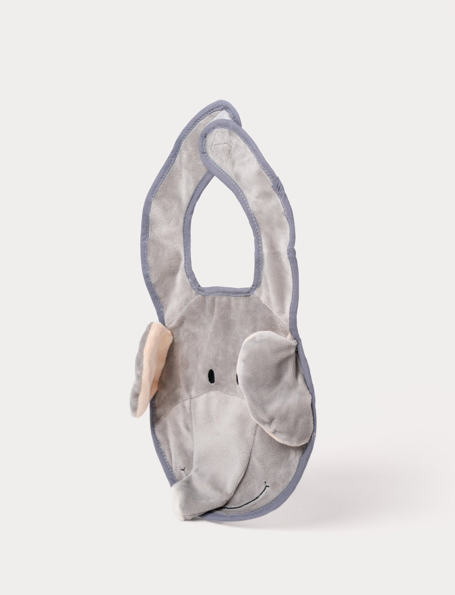 A grey elephant-shaped baby bib with floppy ears, a soft trunk, and a stitched smiling face.