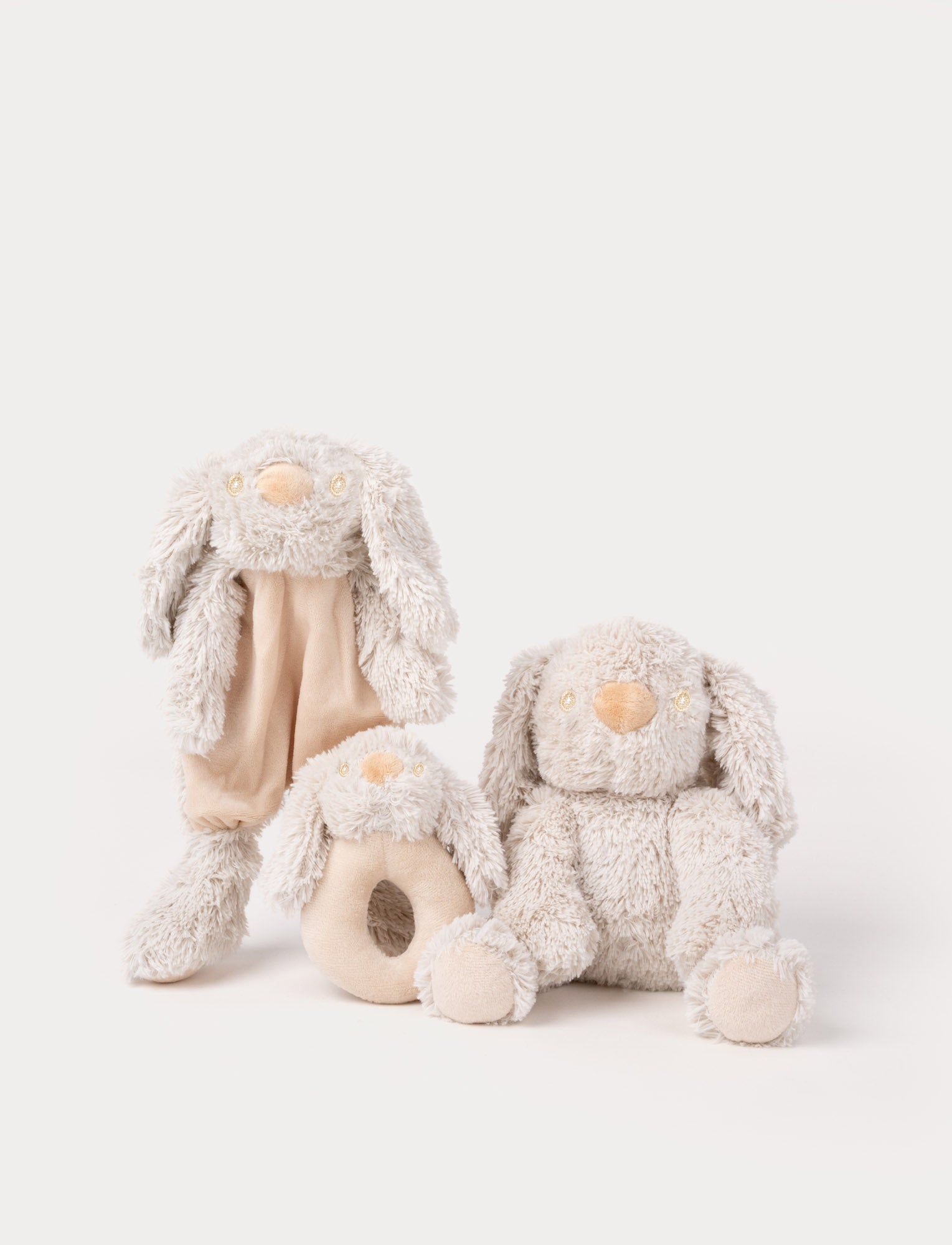Image of Set of three beige bunny plush toys, including a comfort blanket, a rattle, and a soft stuffed rabbit.