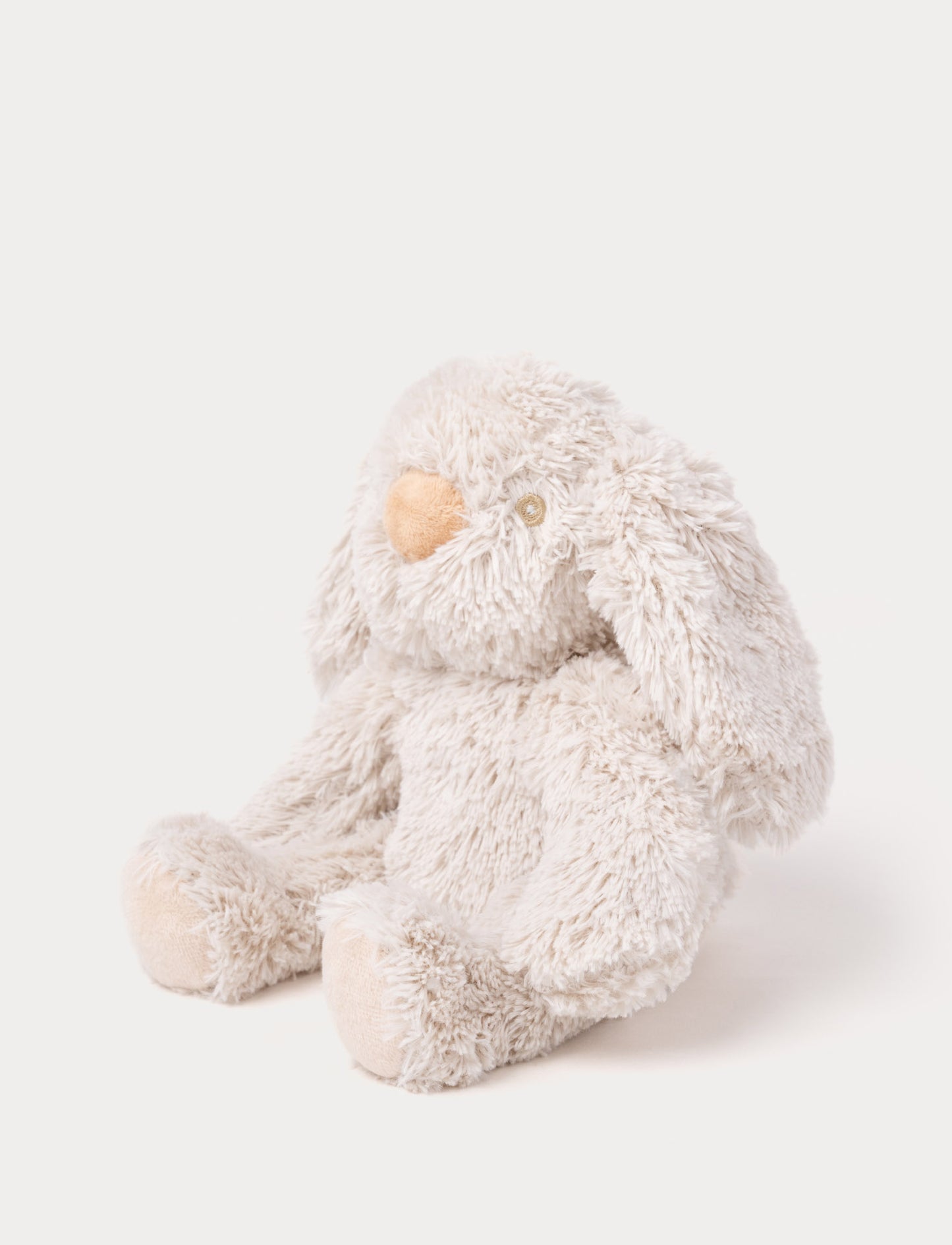A soft beige plush bunny with floppy ears, a brown nose, and golden-stitched eyes.
