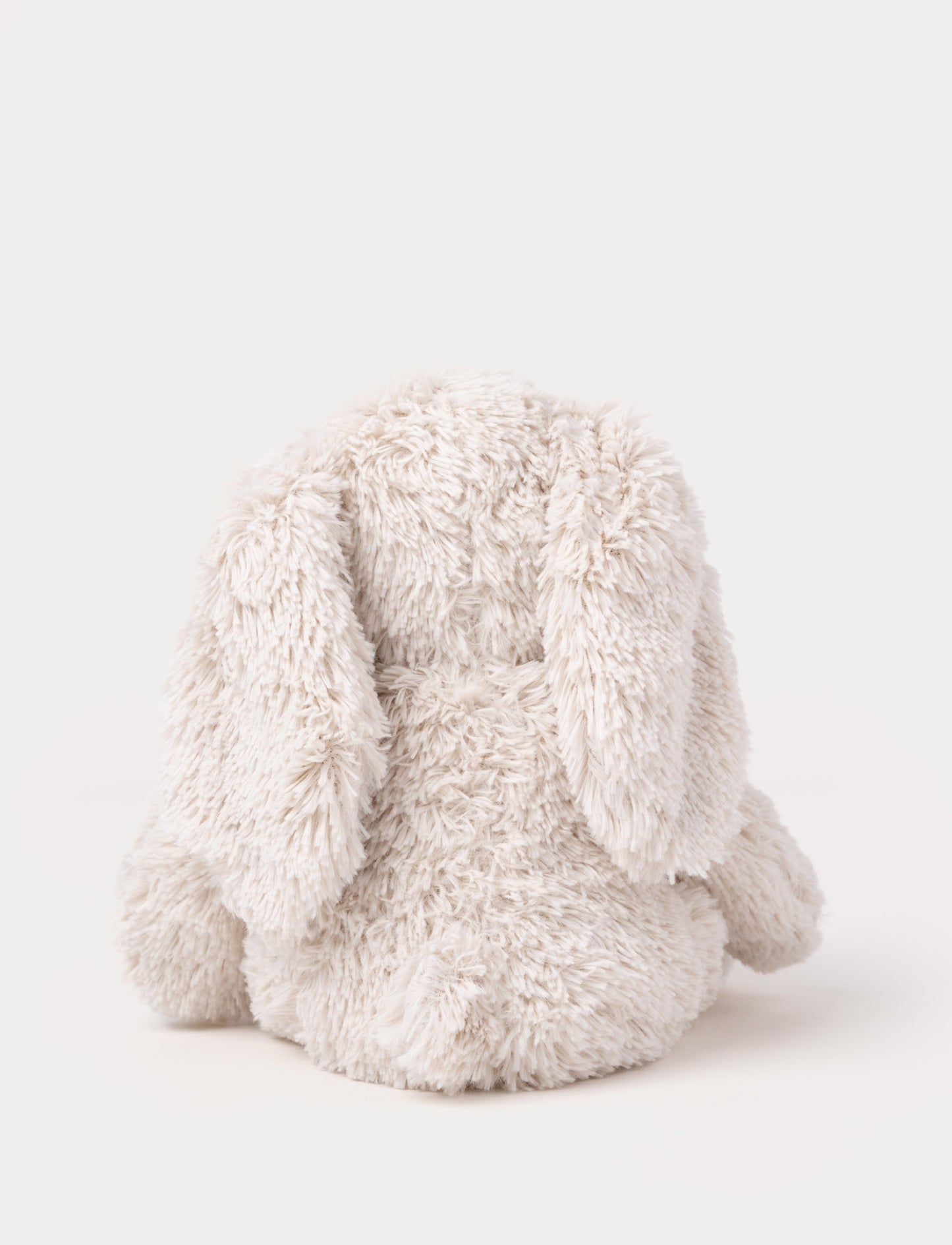 A soft beige plush bunny with floppy ears, a brown nose, and golden-stitched eyes.