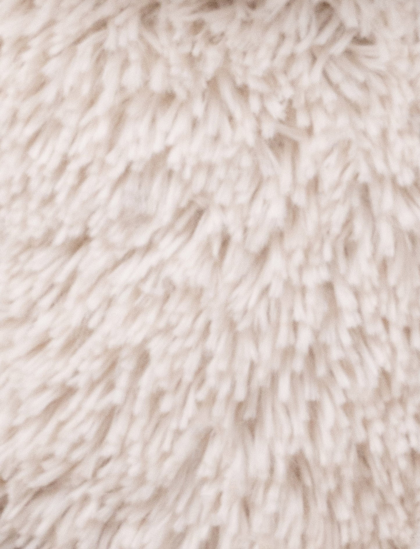 A soft beige plush bunny with floppy ears, a brown nose, and golden-stitched eyes.