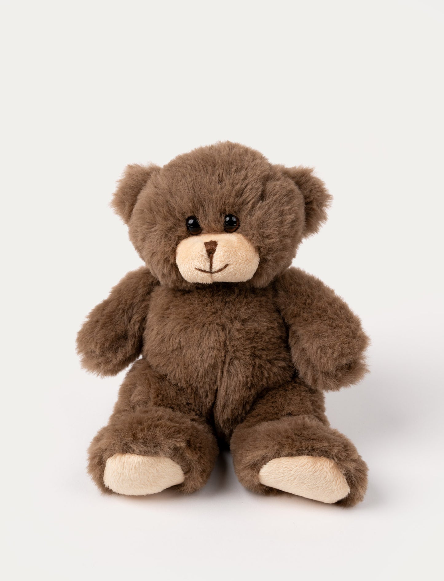 A small brown teddy bear with a yarn nose and lively plastic eyes.