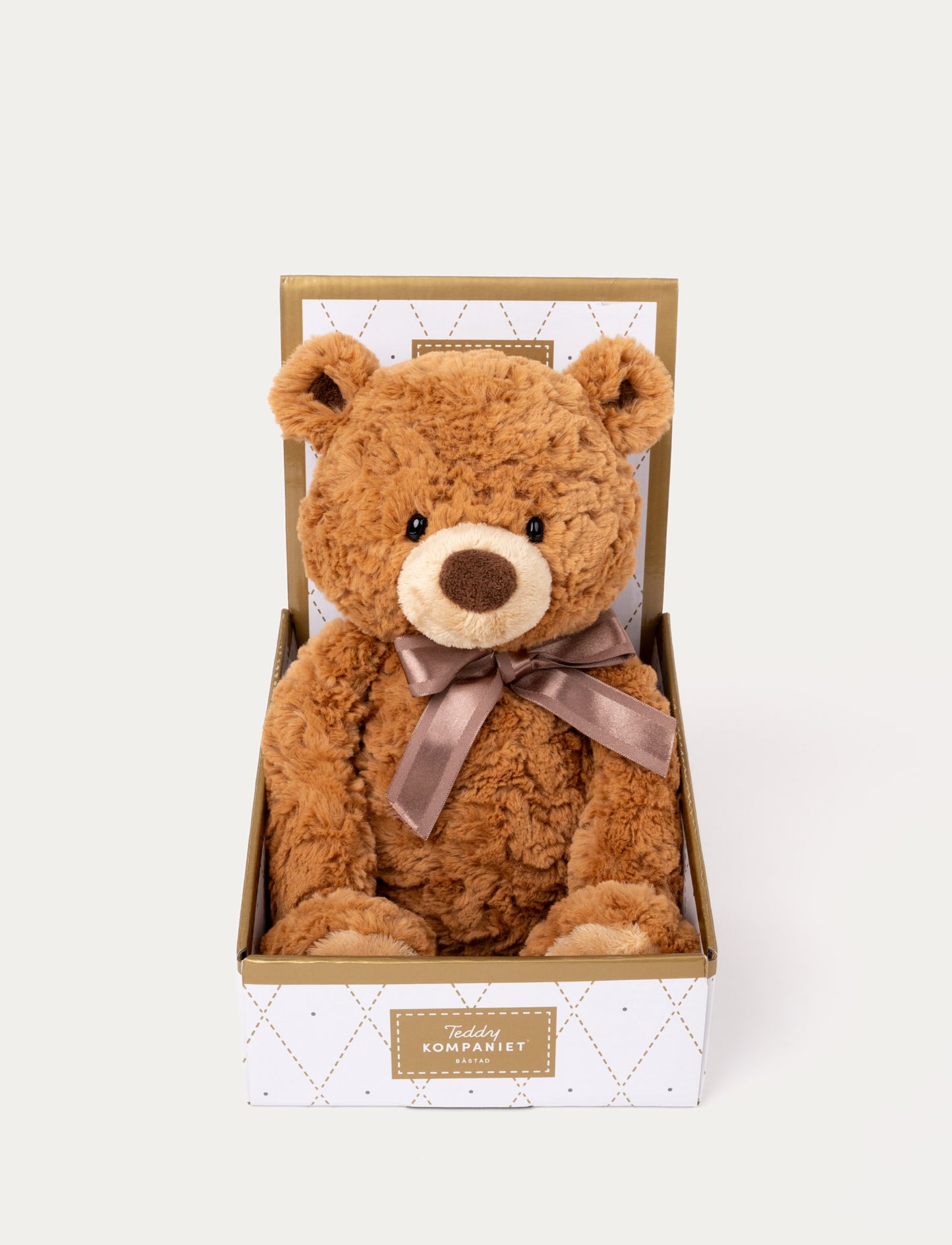 Brown plush teddy bear with a soft, curly texture, a satin ribbon around its neck, and presented in a decorative gift box.