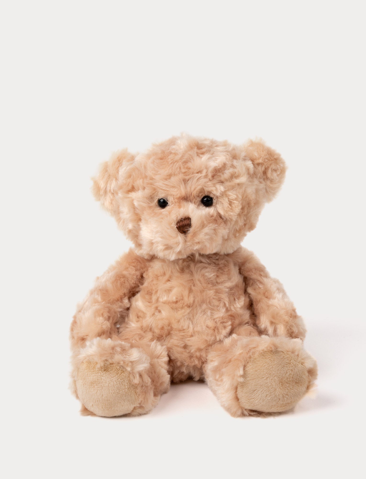 Image of Soft, curly beige teddy bear plush with black eyes, a brown nose, and stitched paw pads.