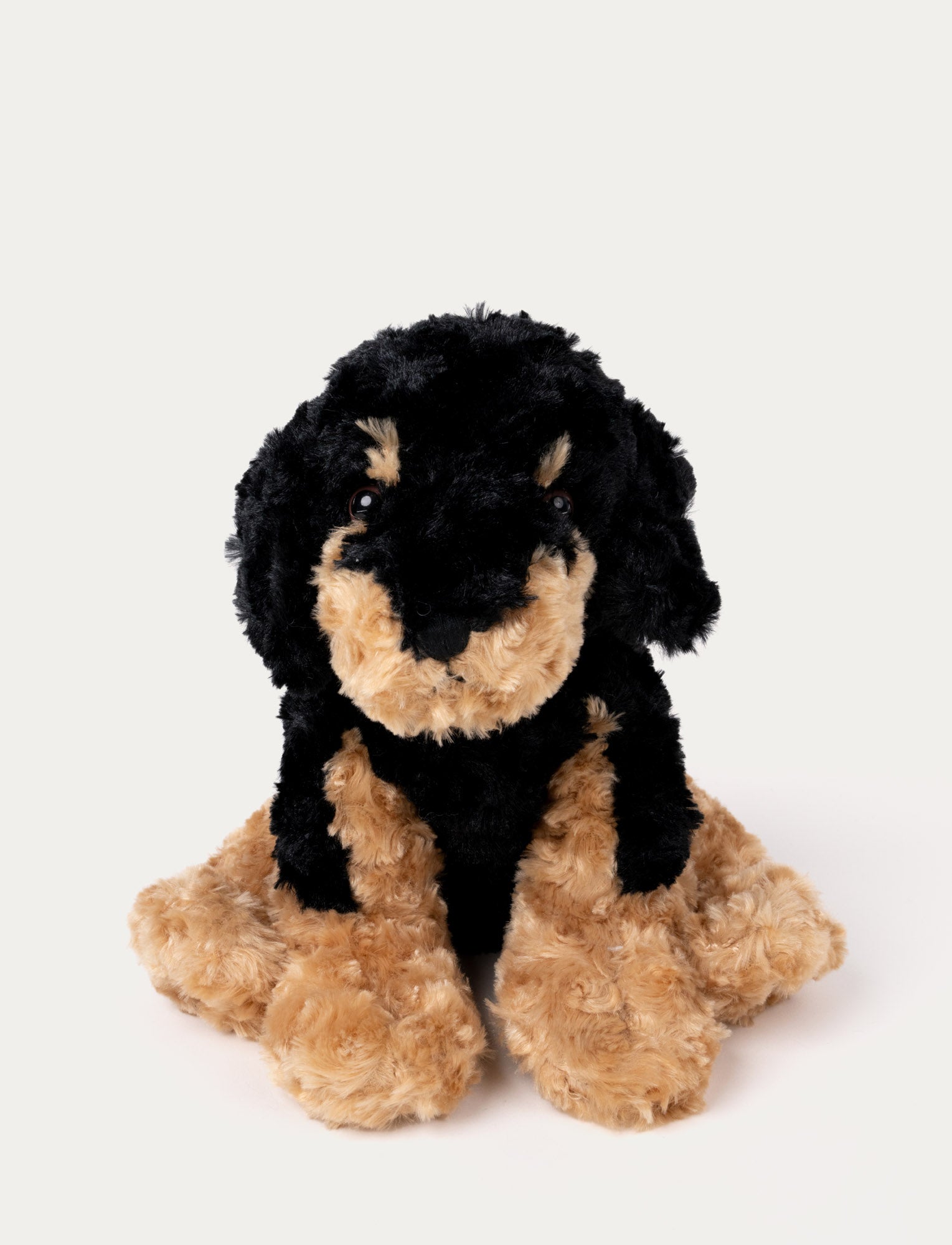 Image of Soft black and tan plush dog with floppy ears, black eyes, and a curly fur texture.