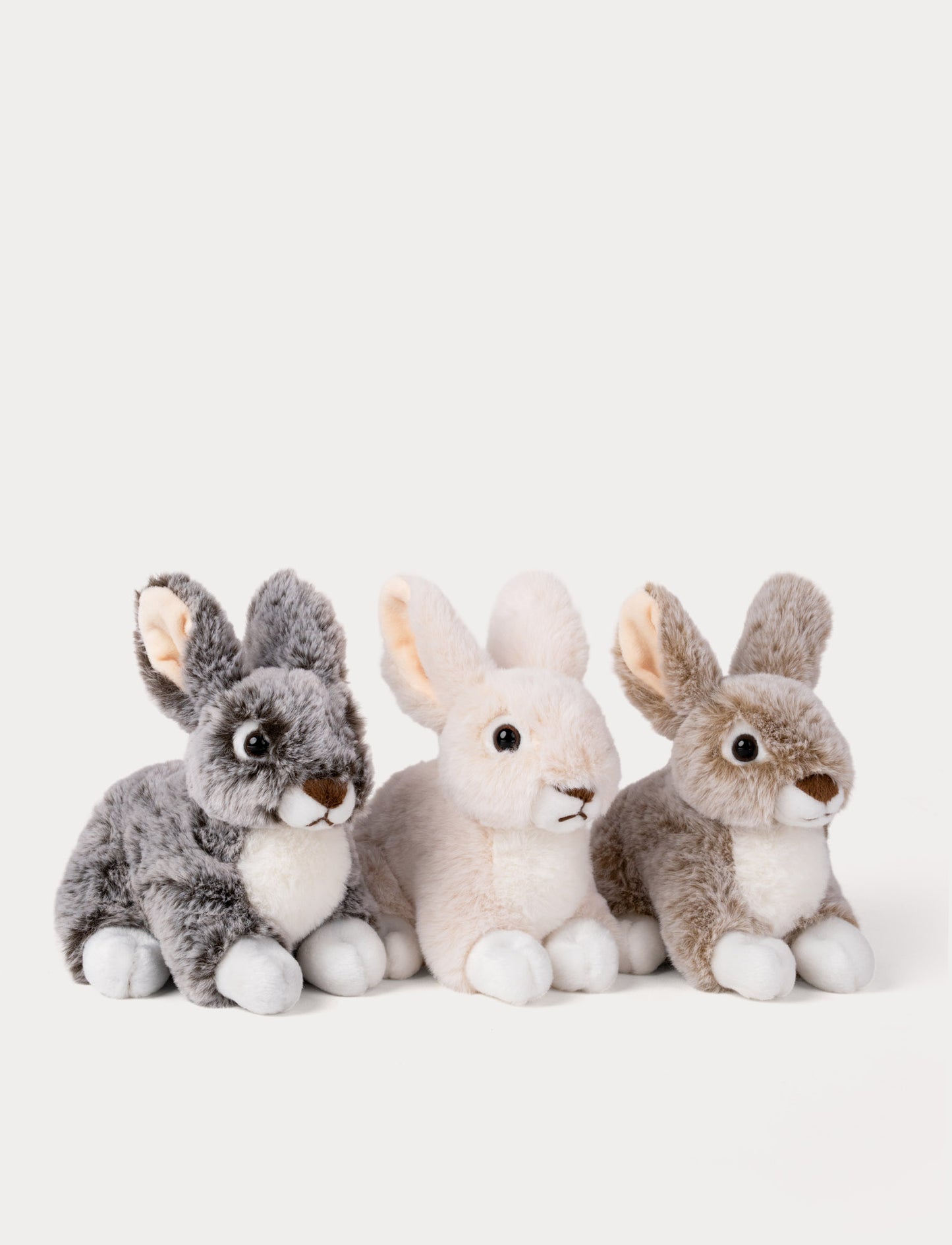 Three plush rabbit toys in gray, white, and brown on a light gray background