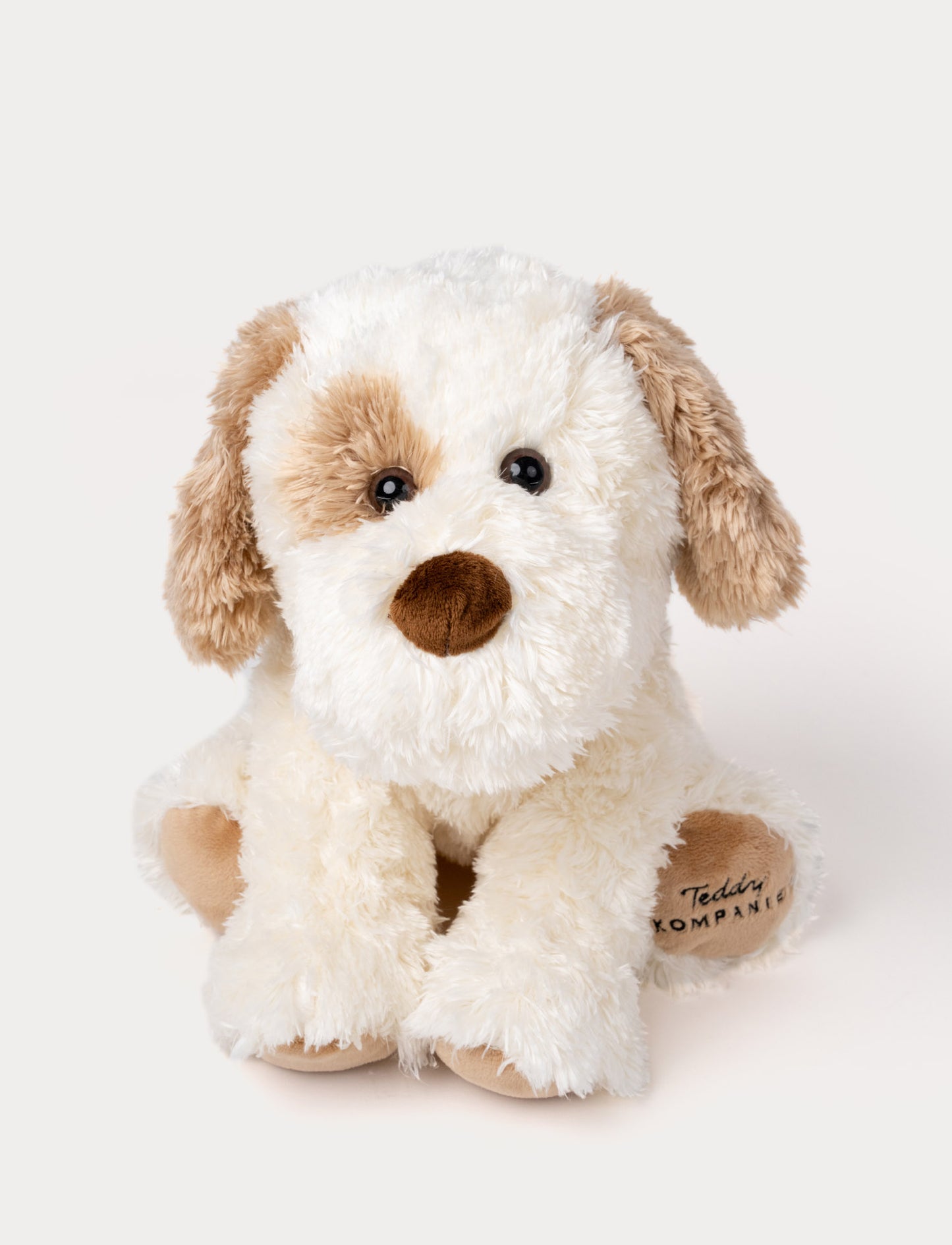 Soft, plush dog with fluffy white and light brown fur, black button eyes, a brown nose, and embroidered text on one paw.