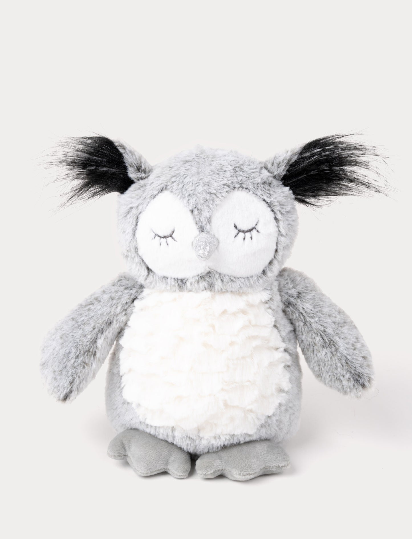 An owl with soft gray fur, a white belly, long ear tufts, and a shimmering silver beak.