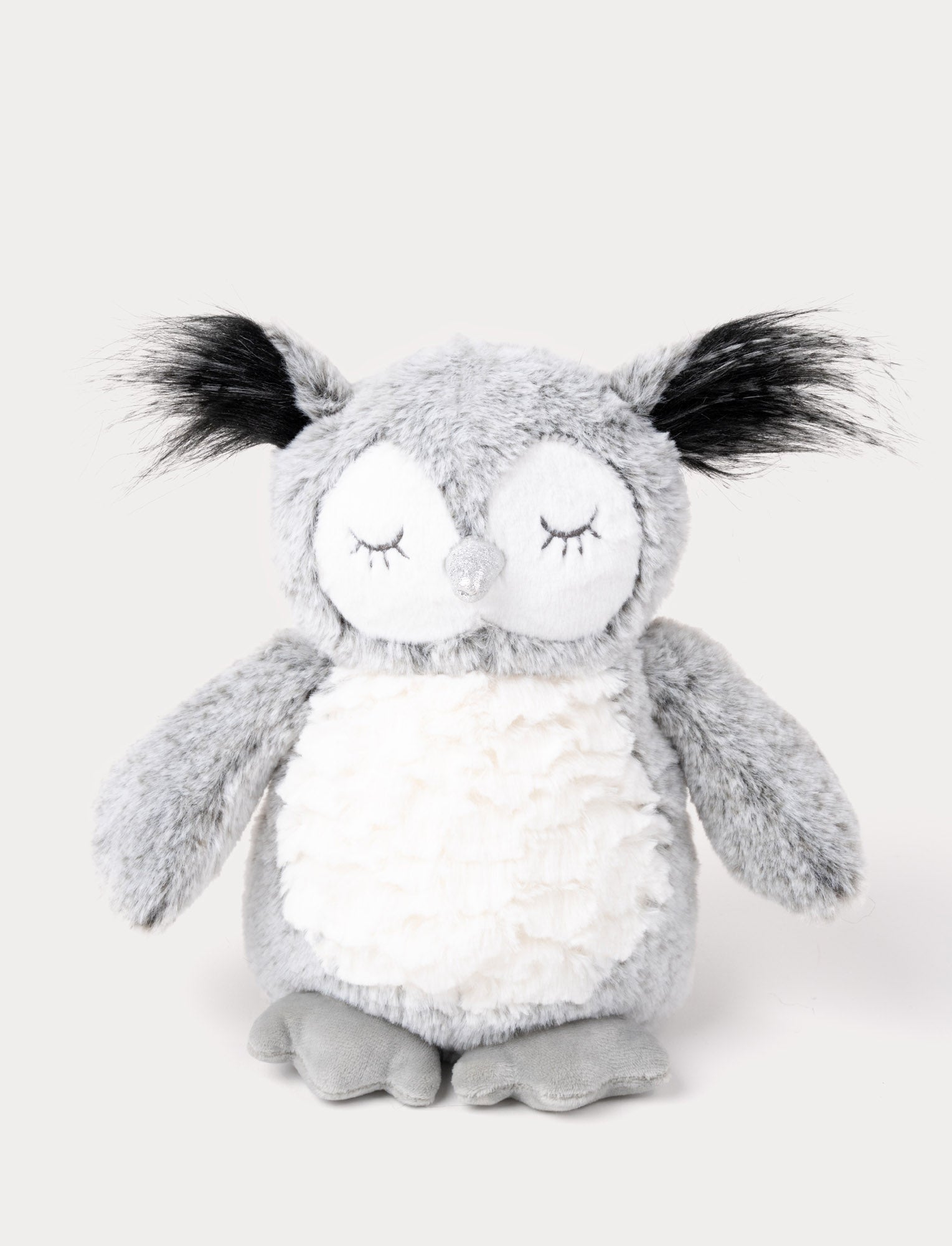 Image of An owl with soft gray fur, a white belly, long ear tufts, and a shimmering silver beak.