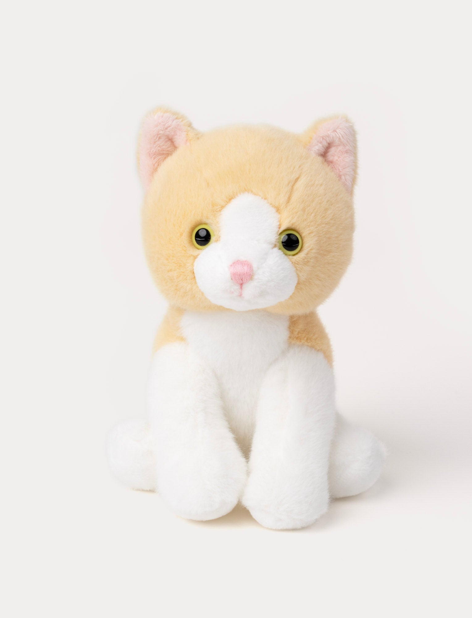 Image of Soft plush cat with light orange fur, white face and paws, round yellow eyes, and a pink nose.