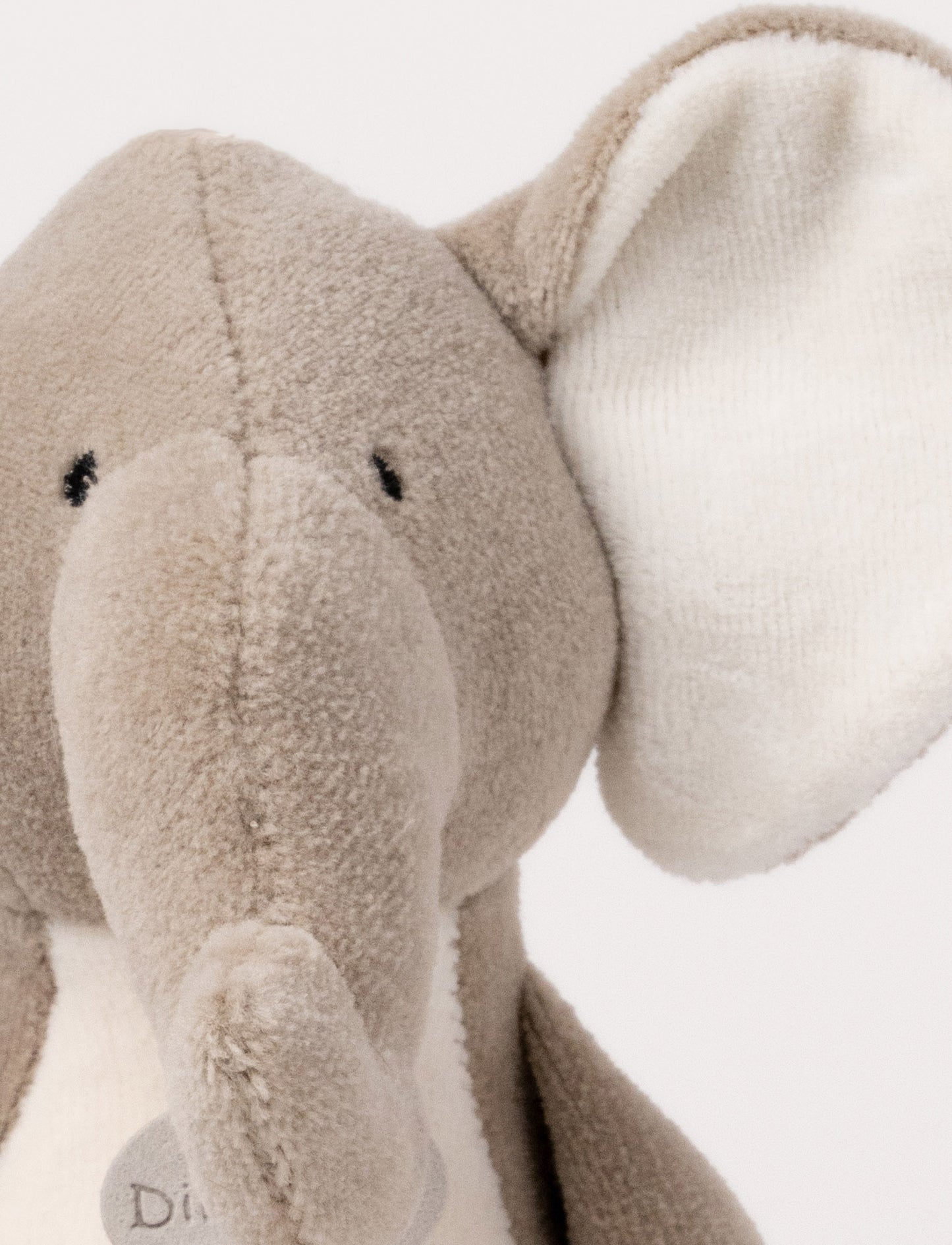 A soft plush beige bunny  with broaded eyes and nose, white, and brown details.