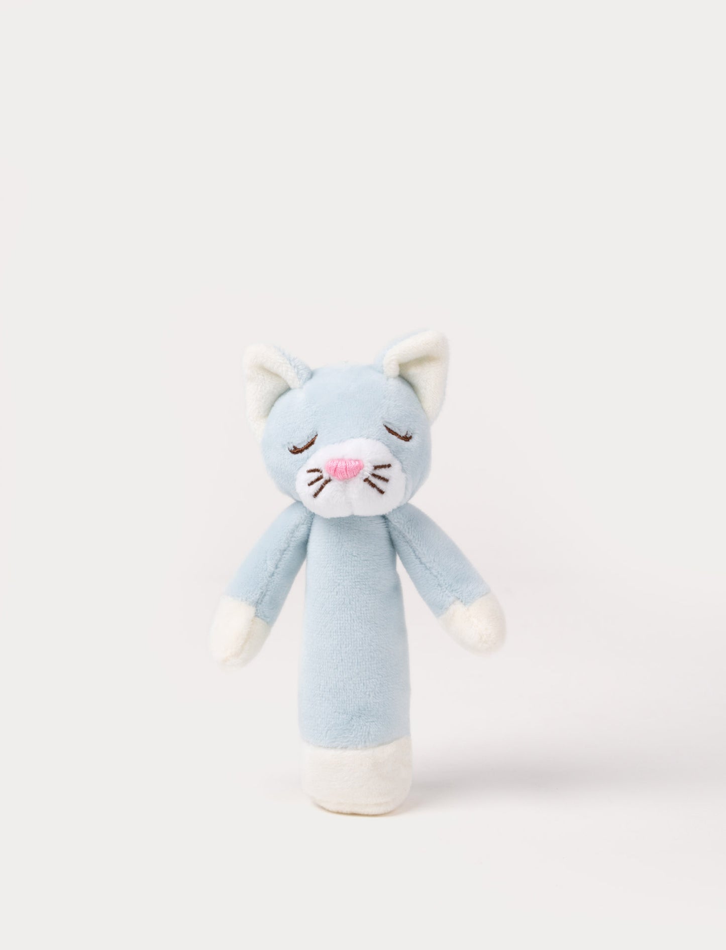 Soft plush cat rattle with a light blue body, embroidered sleeping eyes, a white muzzle, and white accents on the hands and base.