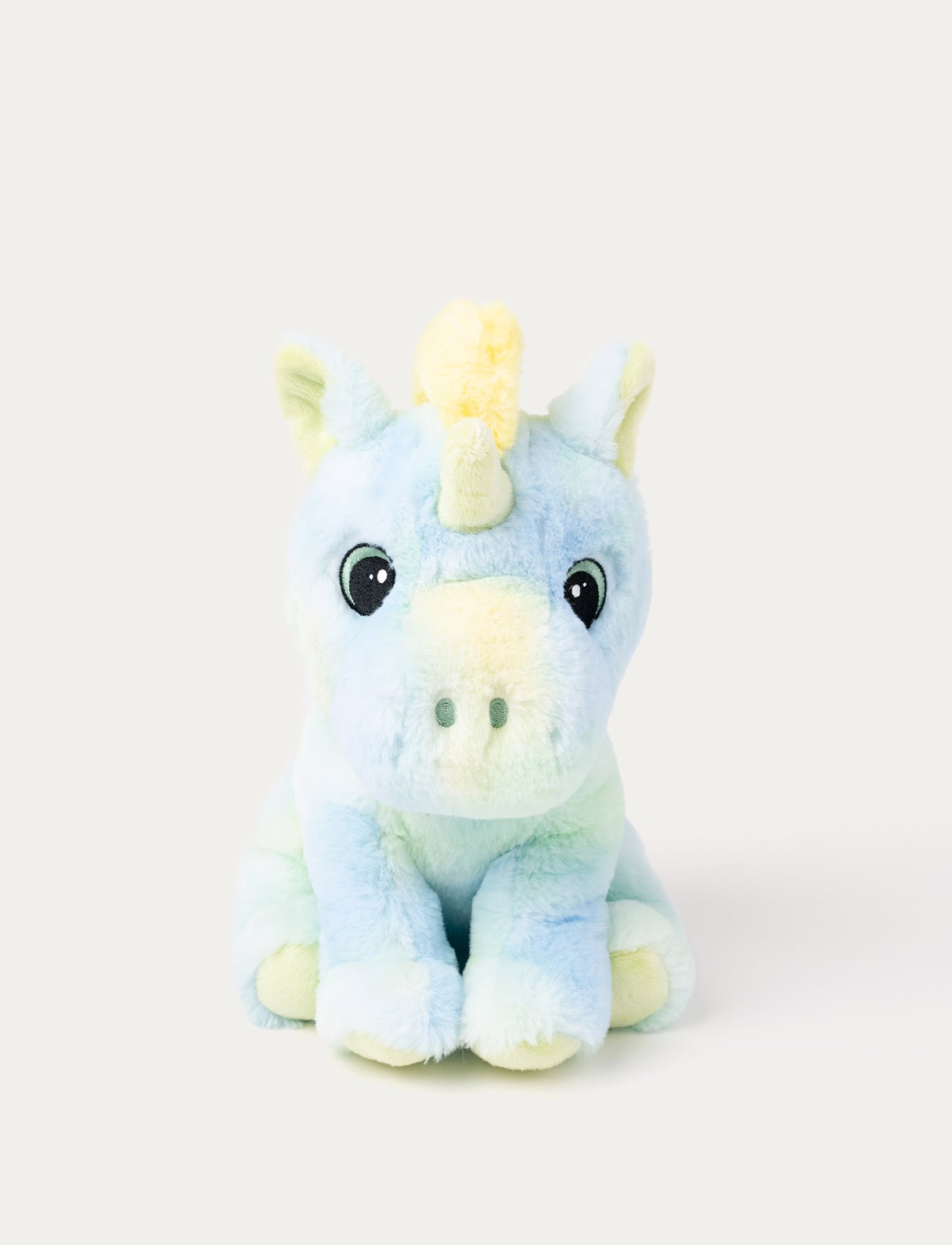 A pastel rainbow unicorn with soft fur, embroidered eyes, yellow, blue, & green shades.