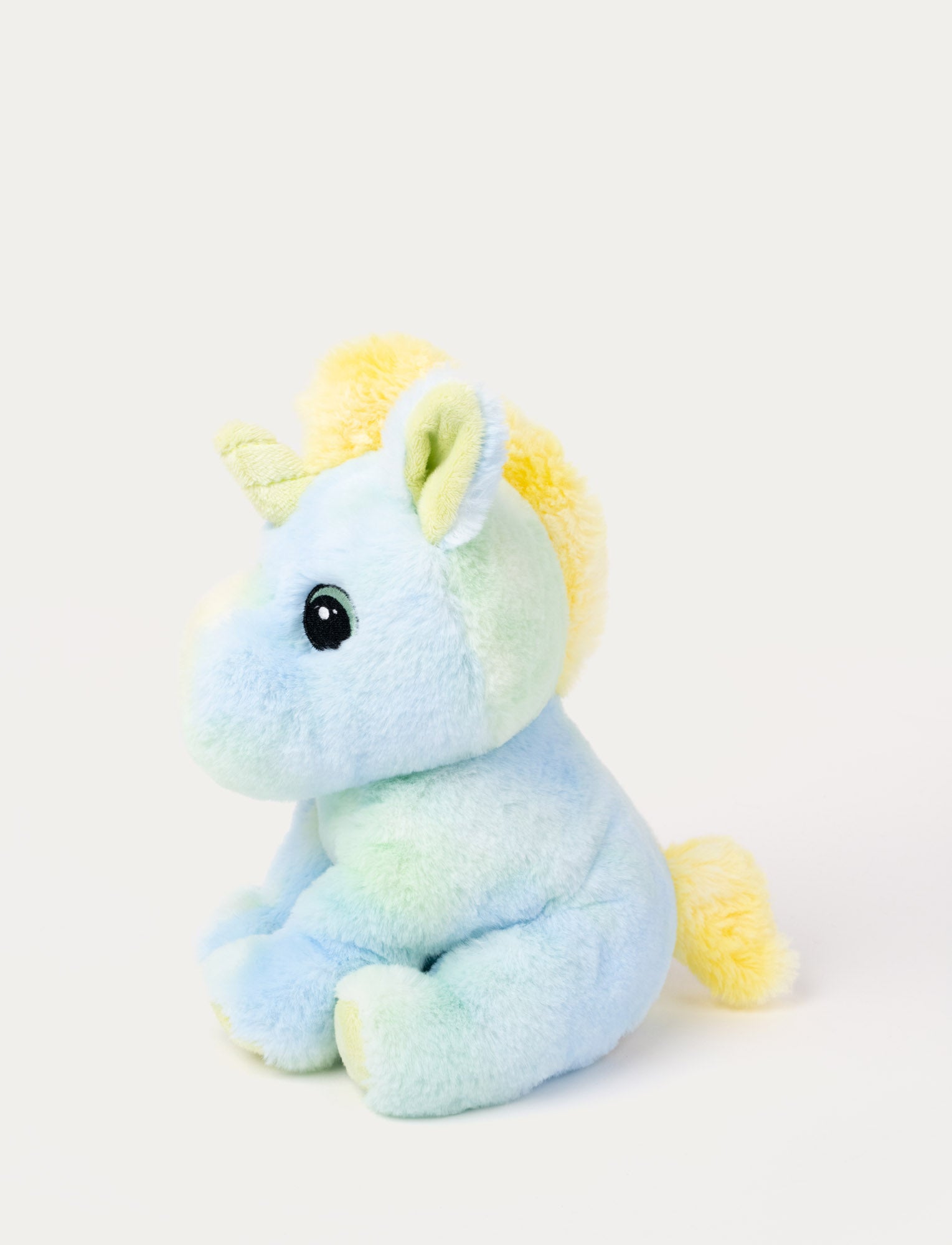 Image of A pastel rainbow unicorn with soft fur, embroidered eyes, yellow, blue, & green shades.
