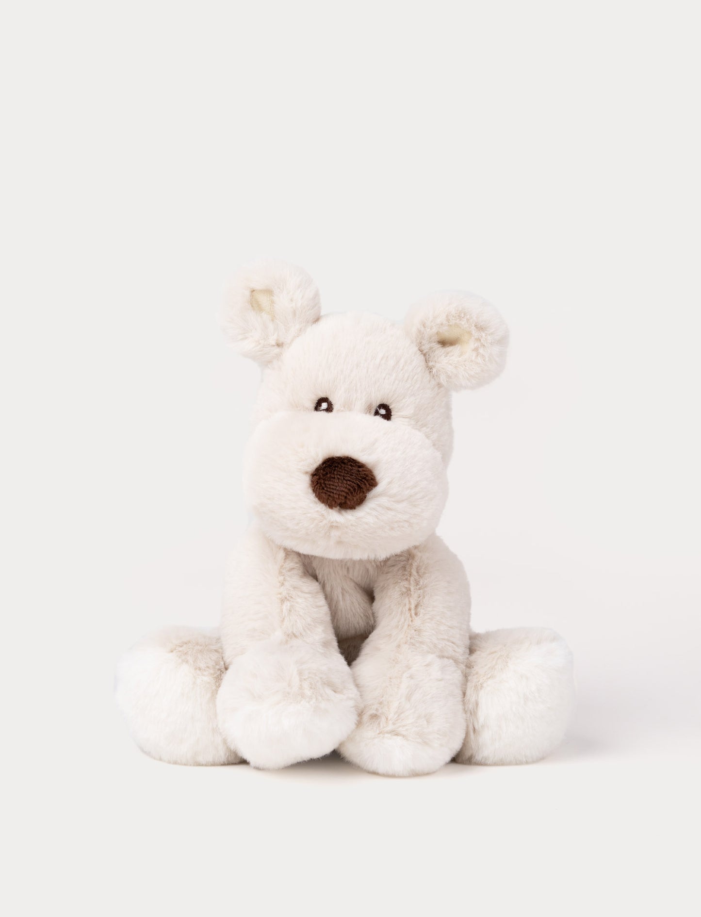 A beige plush dog with soft fur, faux suede detail on its back, and embroidered eyes.