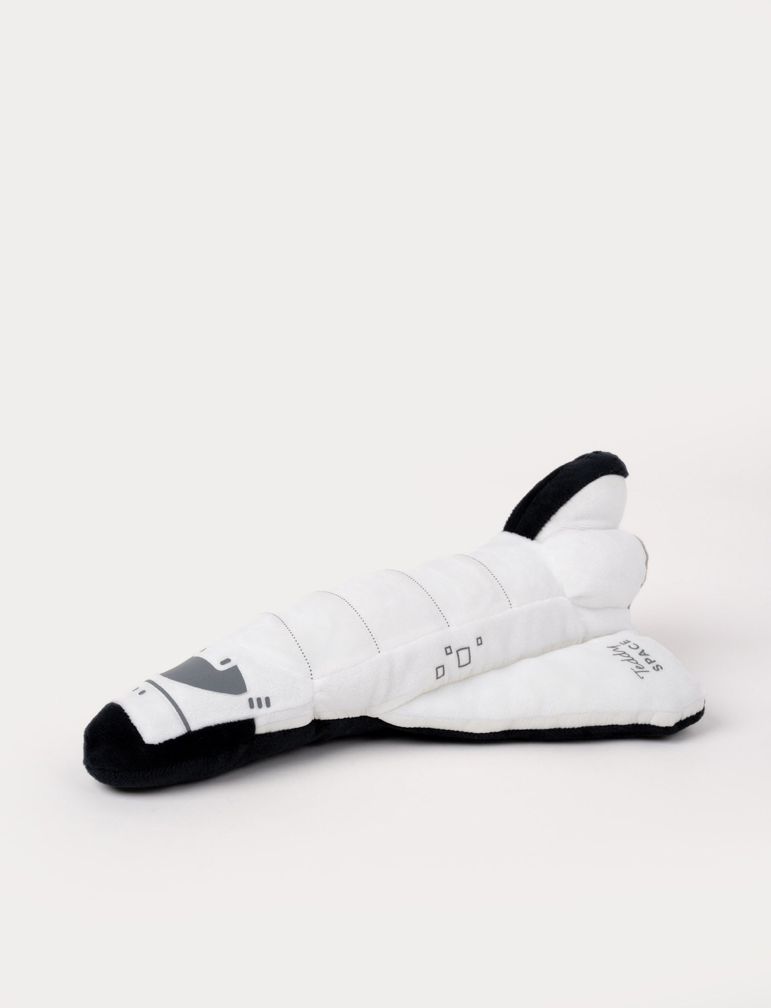 Image of Soft white space shuttle plush with black accents, embroidered details, and "Teddy SPACE" stitched on the wing.