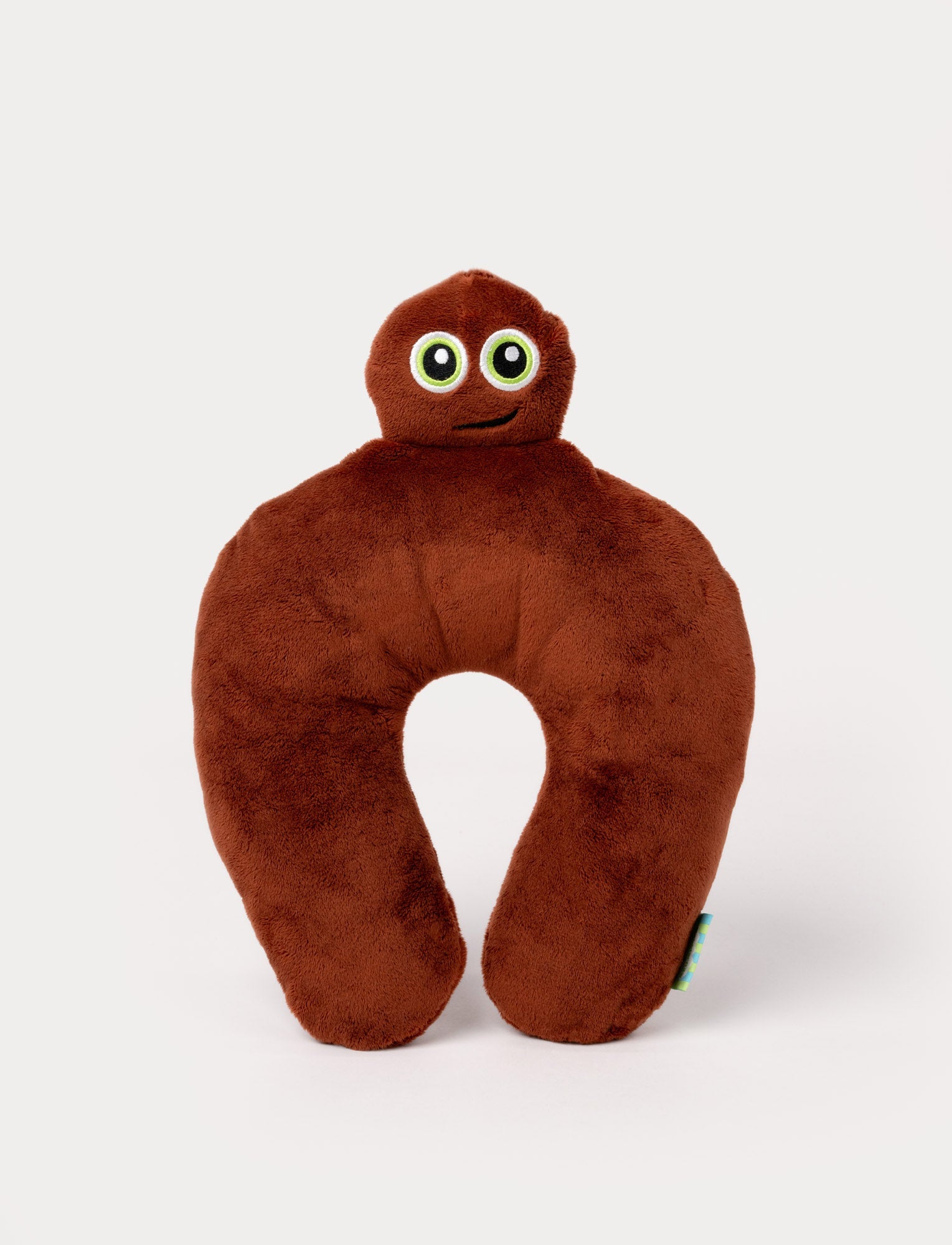  Image of Brown plush neck pillow with a character head, large green eyes, and a friendly embroidered smile.
