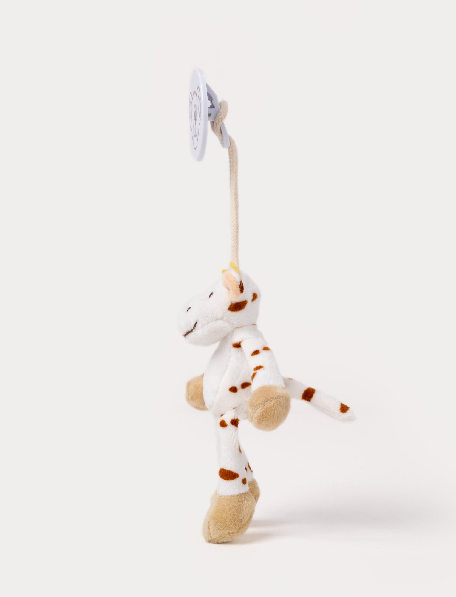  Image of A plush cow clip toy with a white body, brown spots, beige hooves, and a round bear-illustrated clip.