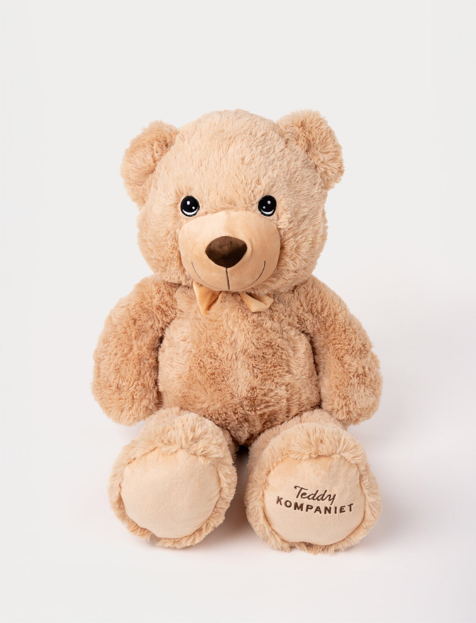  Image of Classic beige teddy bear with a soft bow, embroidered smile, and "Teddy Kompaniet" on one paw.