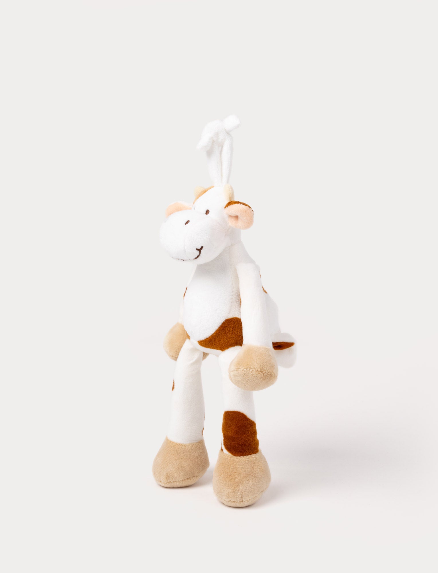  Image of A plush cow music box with brown spots, beige hooves, and a hanging loop.