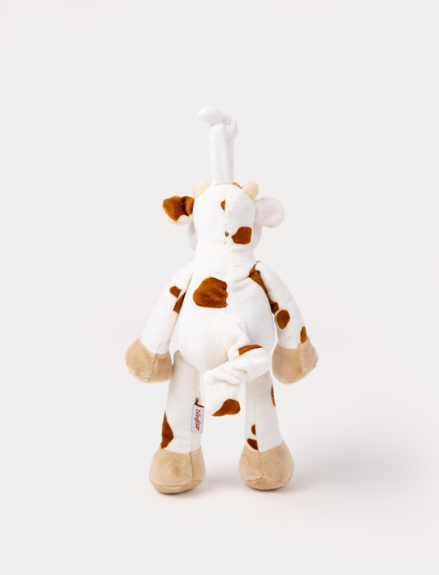  Image of A plush cow music box with brown spots, beige hooves, and a hanging loop.