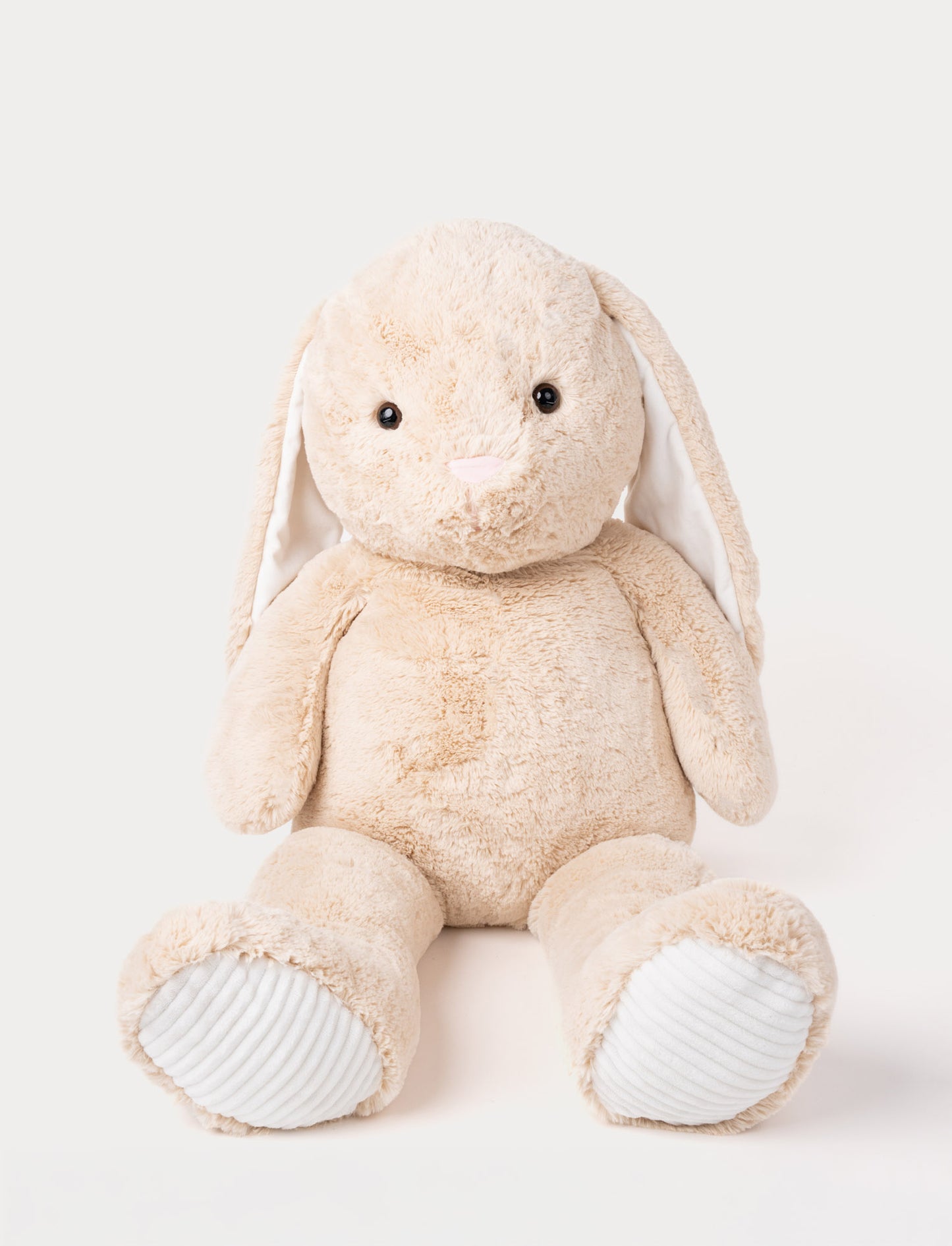 Soft beige plush bunny with long floppy ears, a pink nose, and ribbed white fabric on its paws.