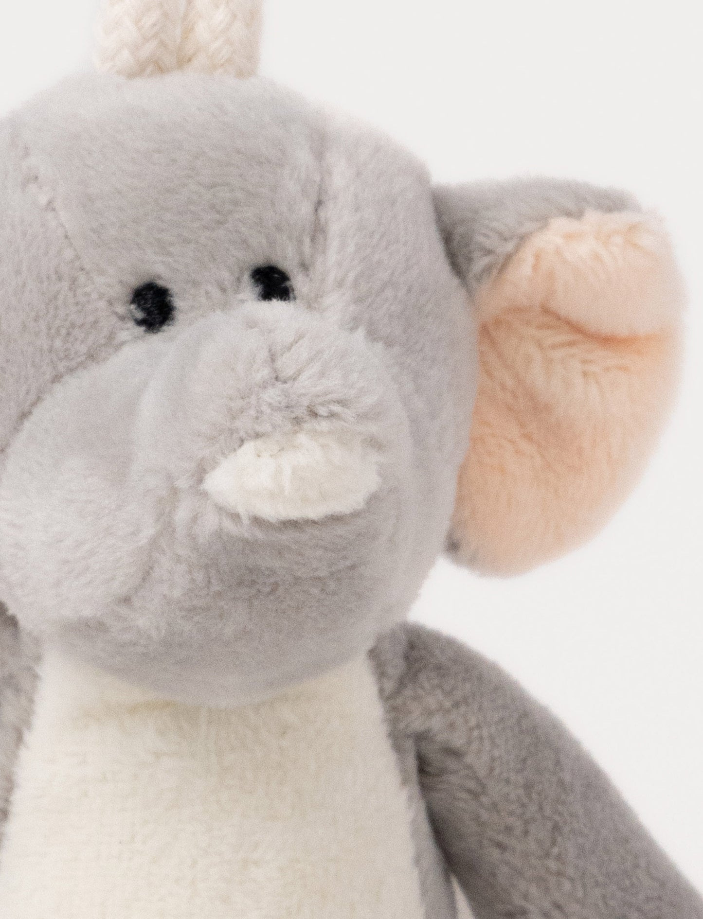 A plush elephant clip toy with large ears, a white belly, beige feet, and a round bear-illustrated clip.