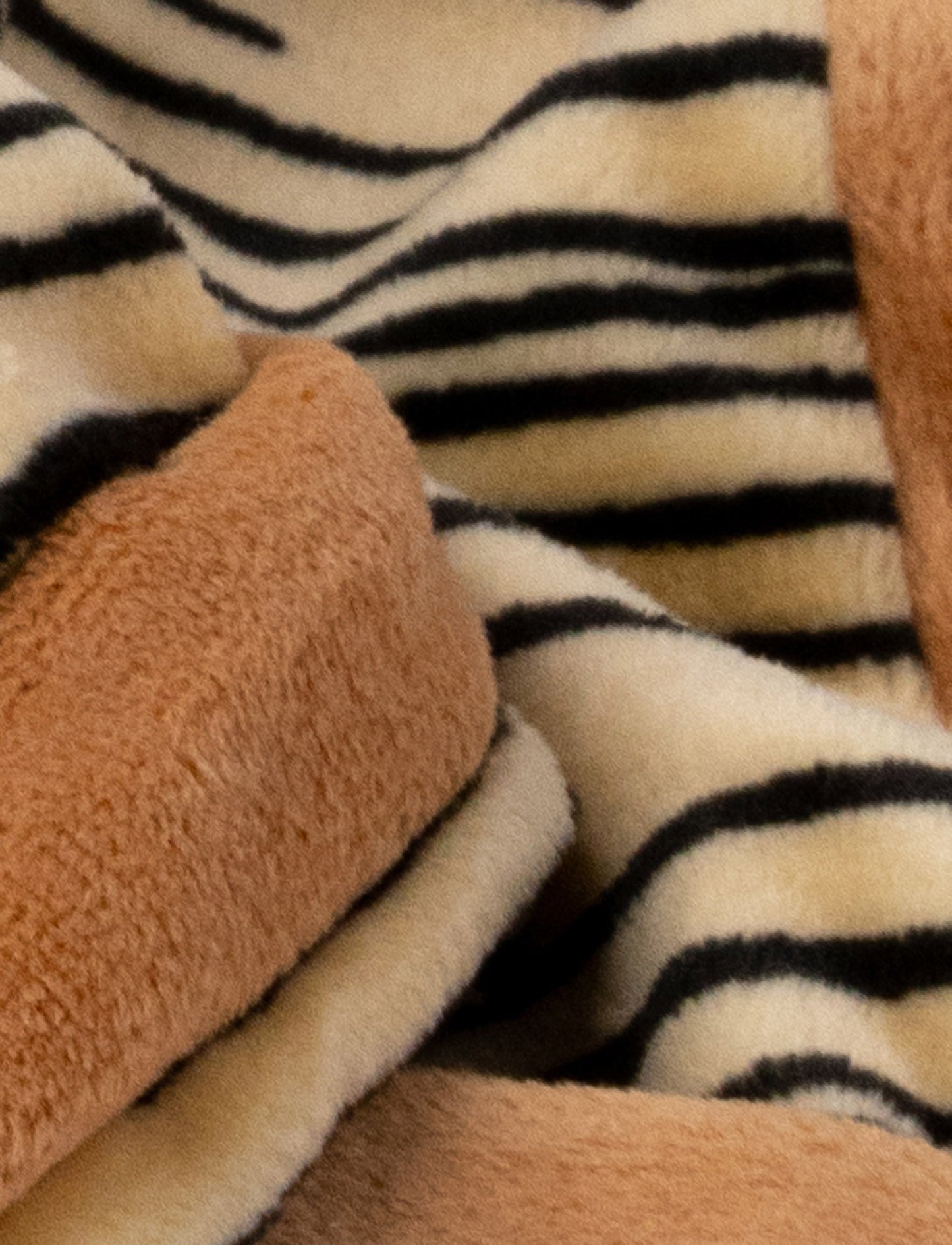 A soft tiger-shaped baby blanket with beige and brown details