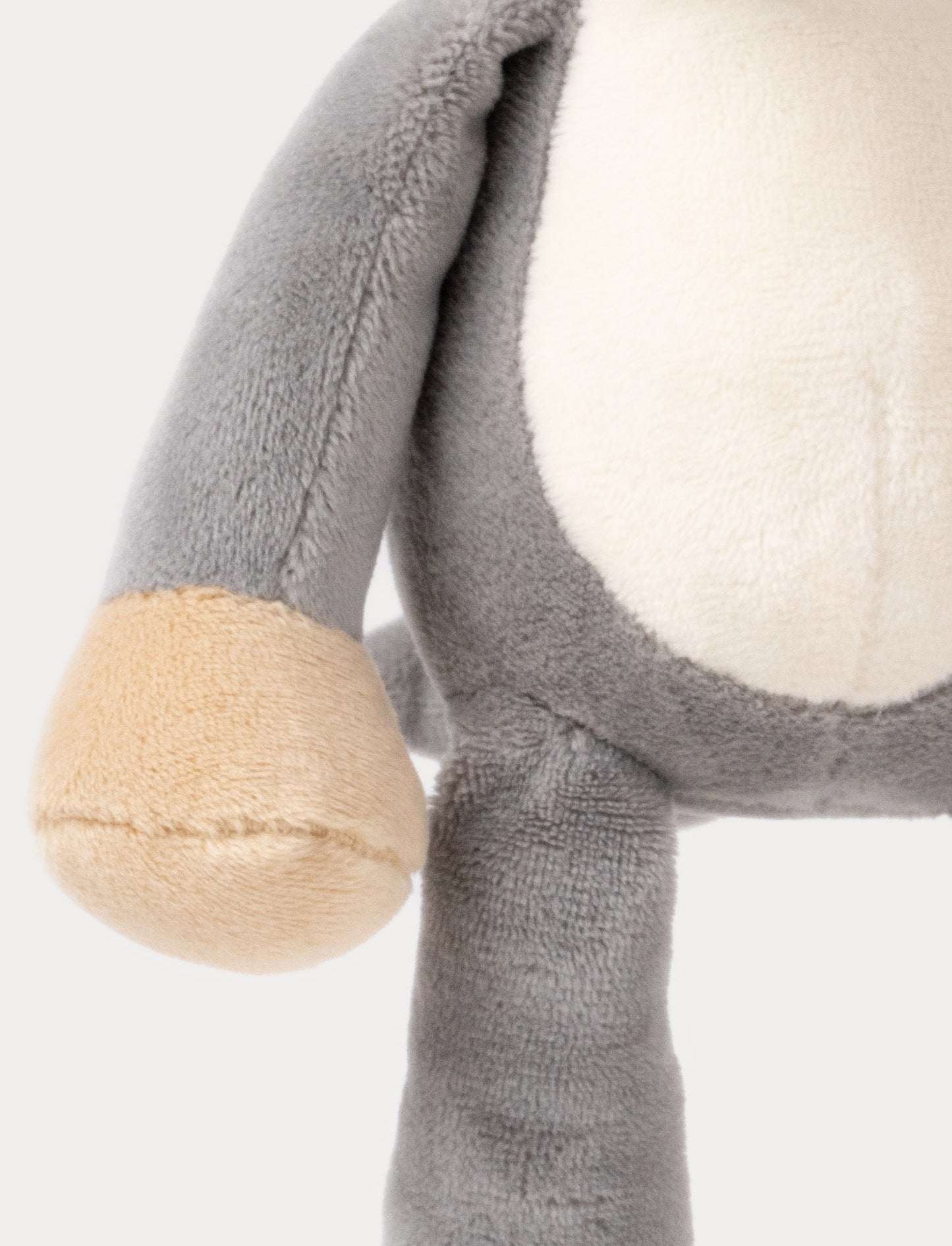 A plush elephant music box with large ears, a white belly, beige feet, and a fabric loop for hanging.