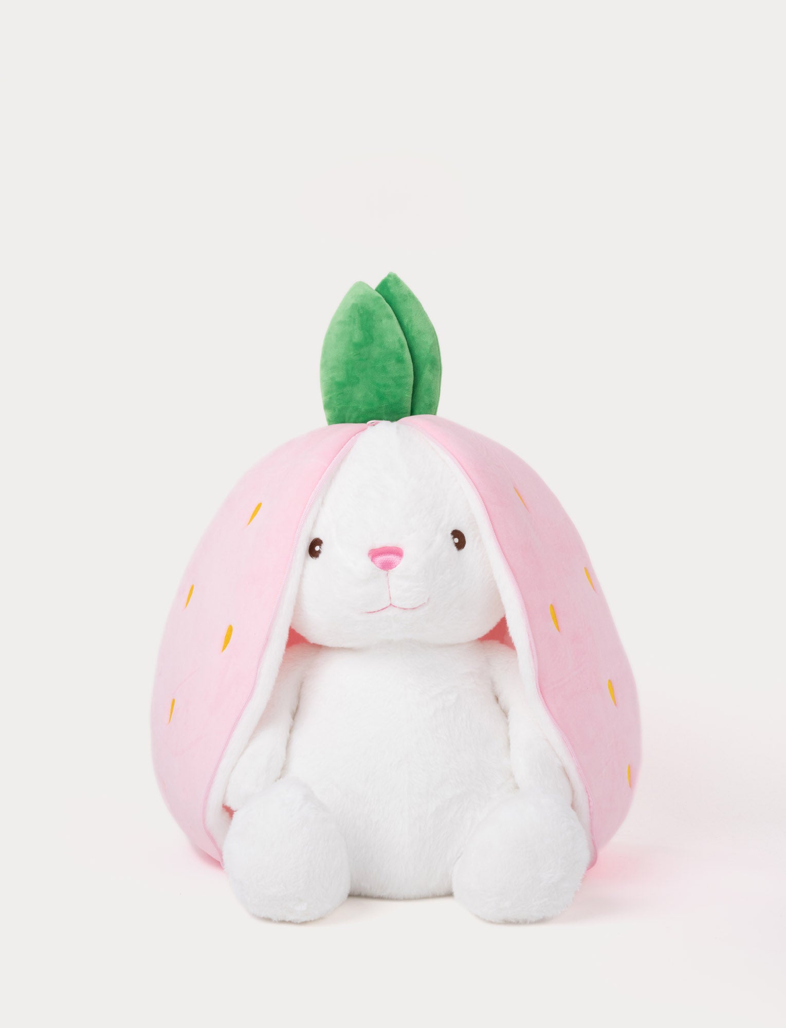  Image of White plush bunny toy sitting inside a soft pink strawberry-shaped zippered cover with green leaves on top.
