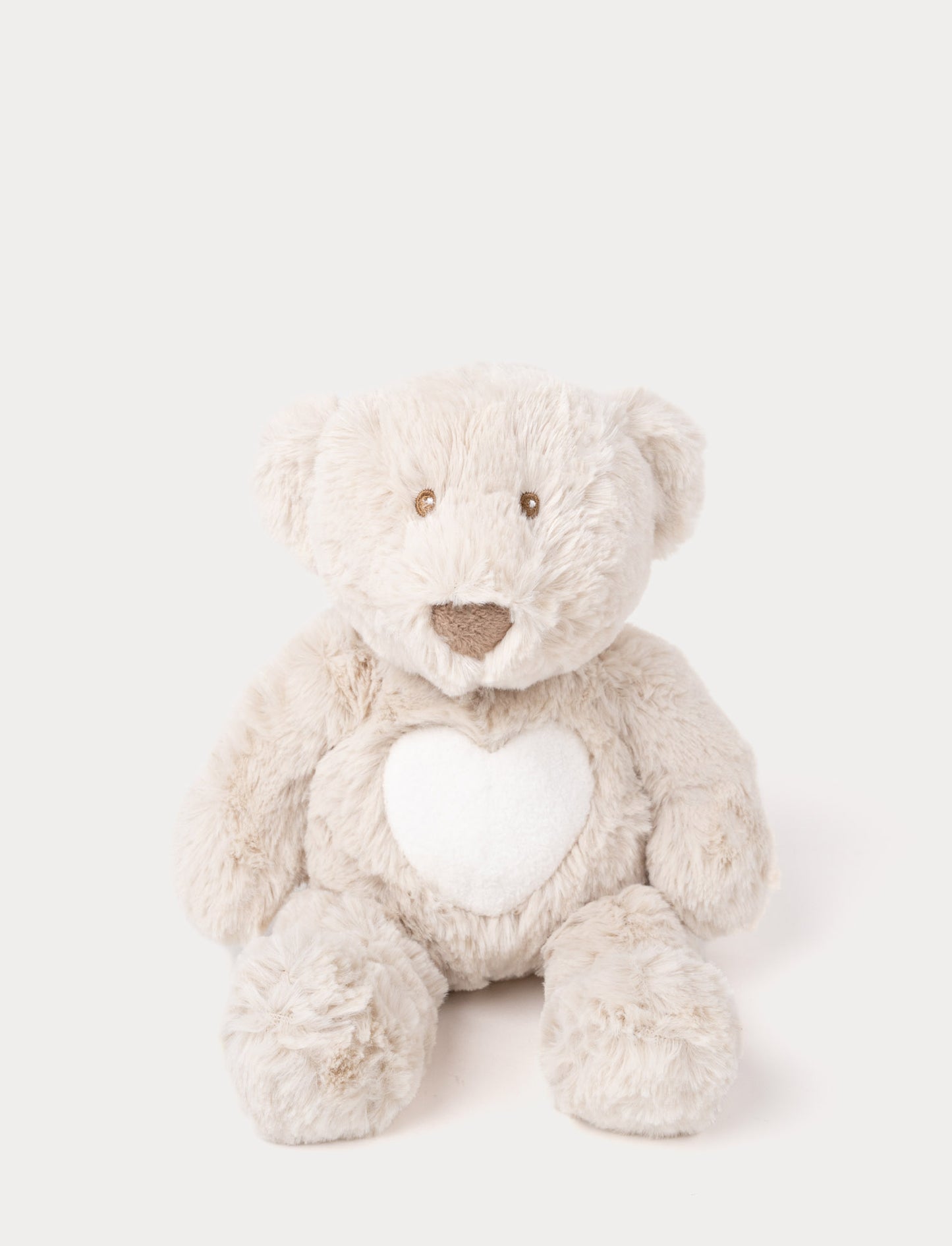 Soft beige teddy with a white heart on his chest and brown stiched eyes