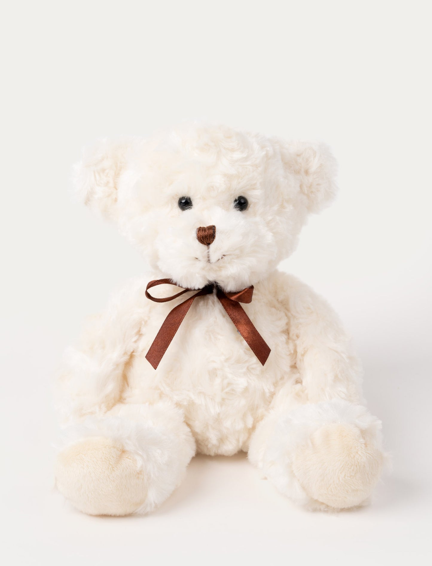 White teddy bear with a brown bow on a light gray background