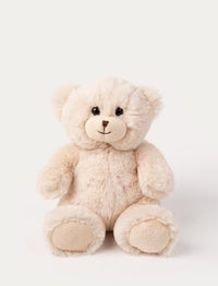A small beige teddy bear with a yarn nose and lively plastic eyes.