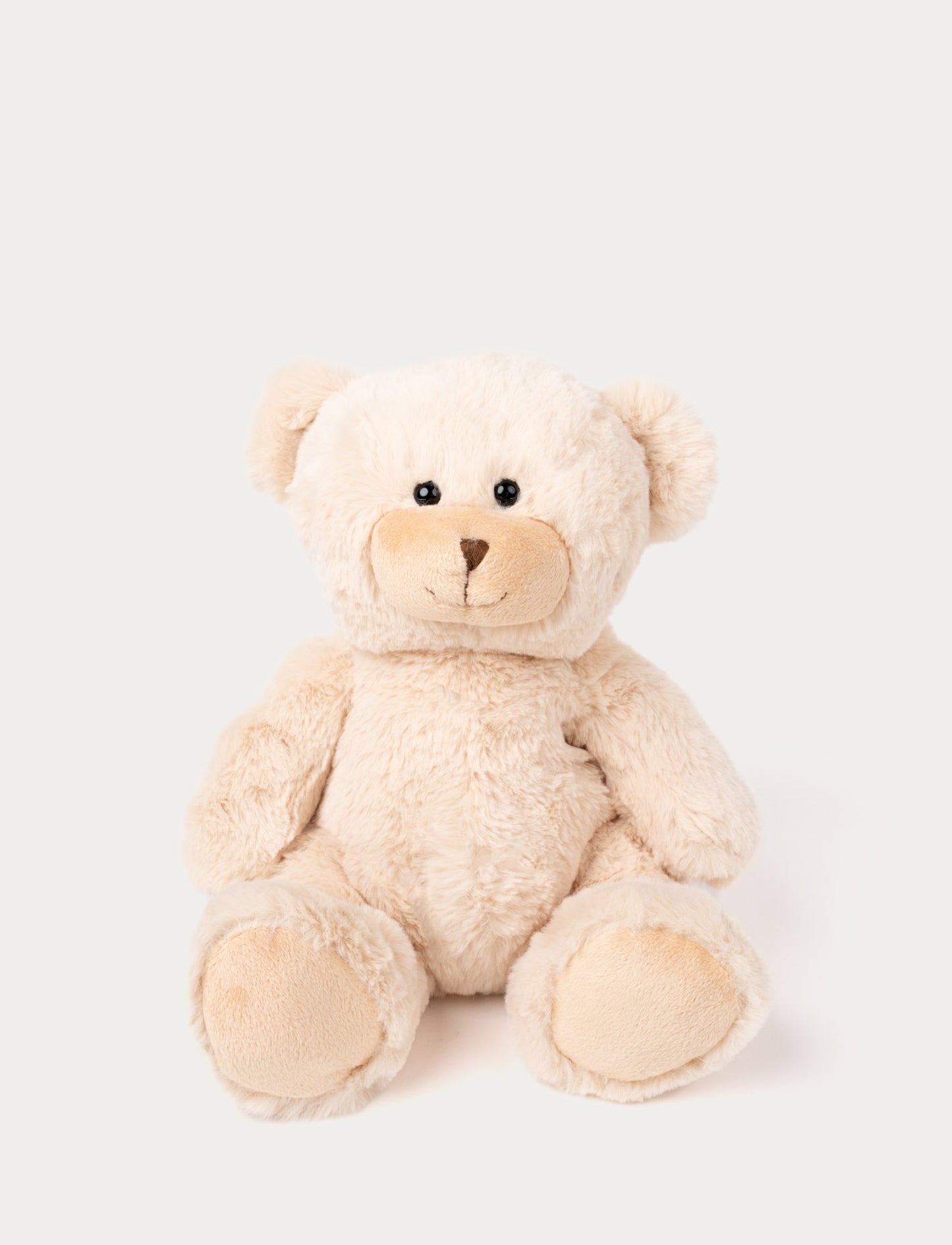 Soft, light beige teddy bear with black eyes and a stitched brown nose