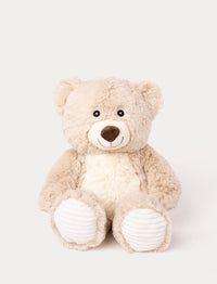 Soft beige teddy bear with a white belly, a stitched smile, and ribbed white fabric on its paws.