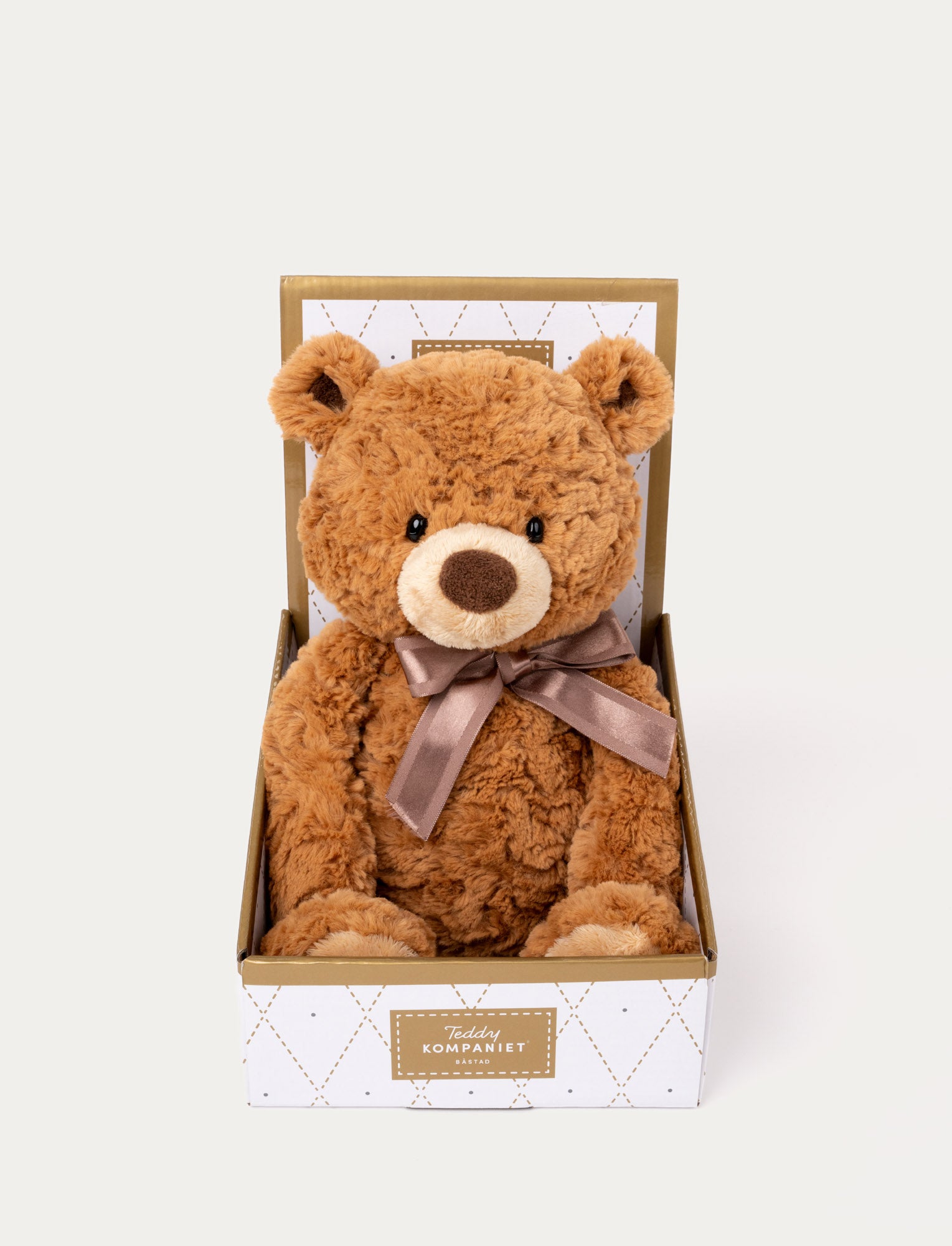  Image of Brown plush teddy bear with a soft, curly texture, a satin ribbon around its neck, and presented in a decorative gift box.