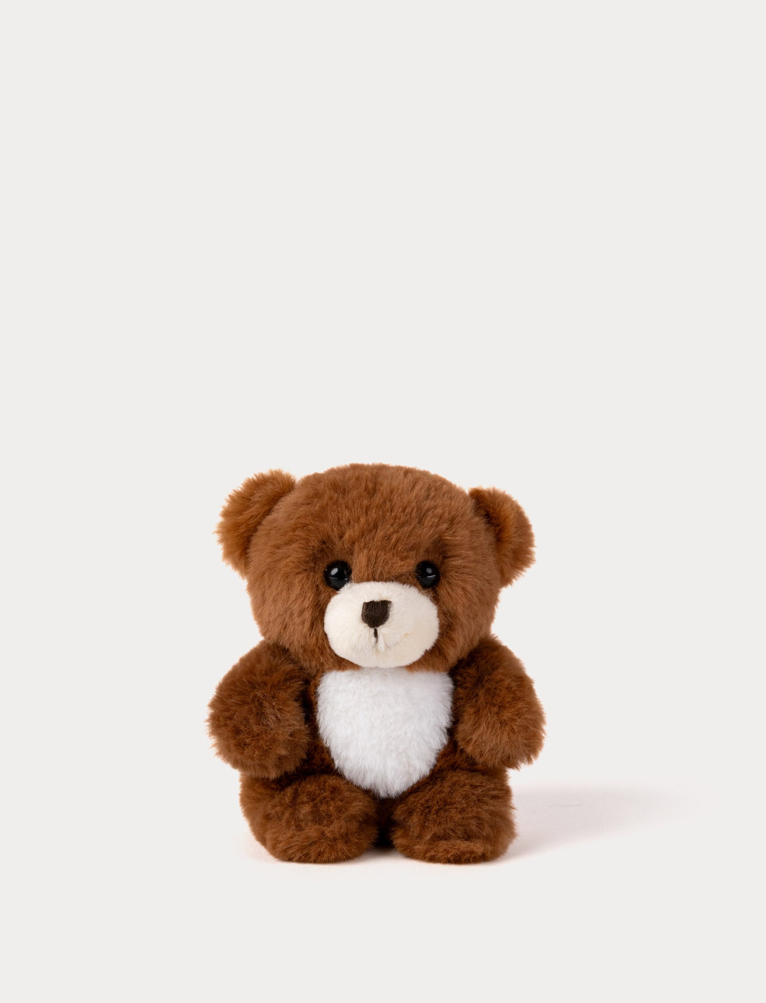  Image of Brown teddy bear with a white belly on a light beige background