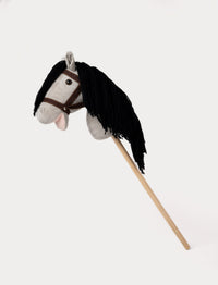 Light gray hobby horse with a soft mane, brown bridle, and a sturdy wooden stick.