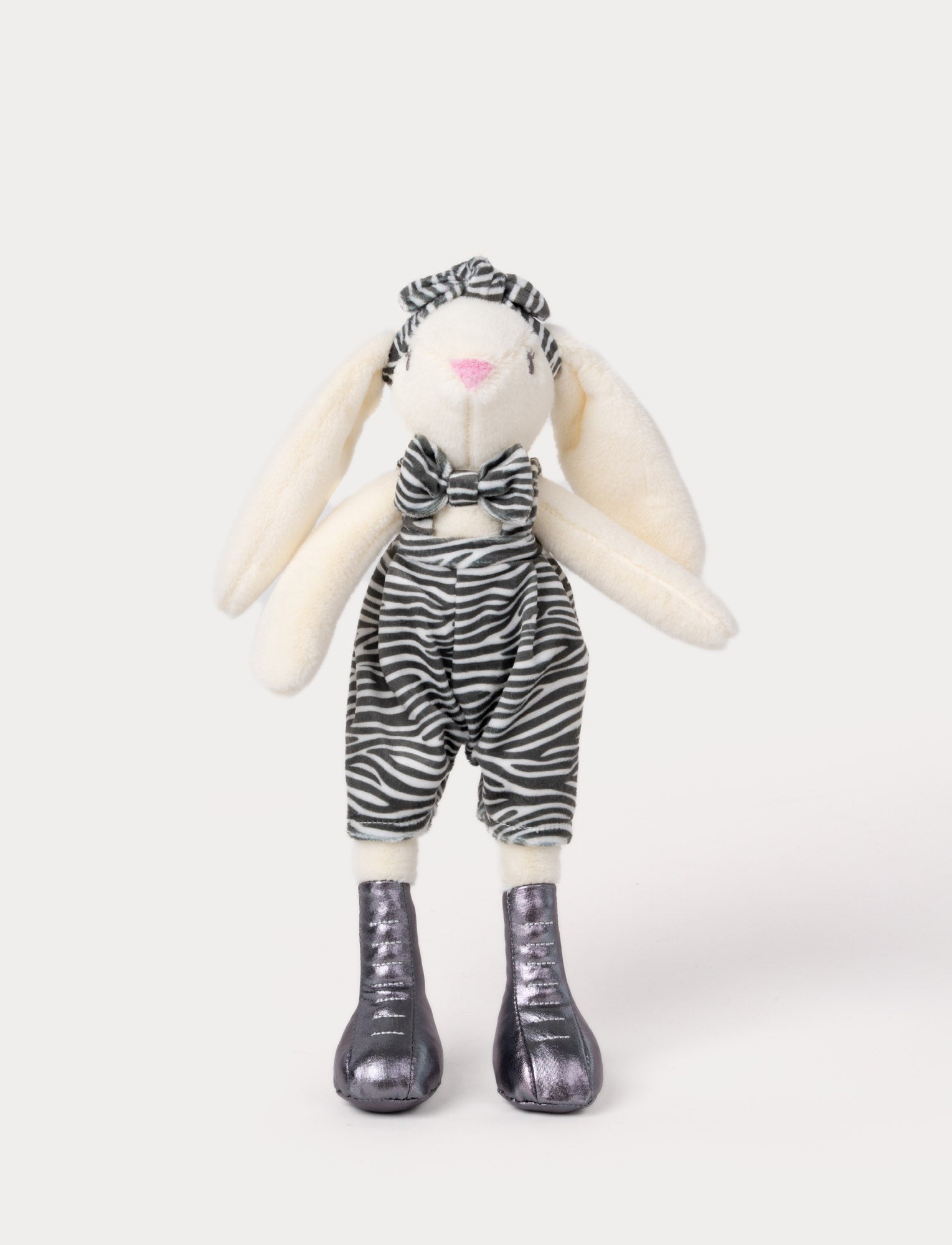  Image of Soft, plush bunny with cream-colored fur, wearing zebra-print overalls, a matching bow, and metallic silver boots.