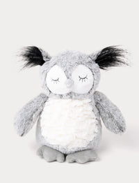 An owl with soft gray fur, a white belly, long ear tufts, and a shimmering silver beak.