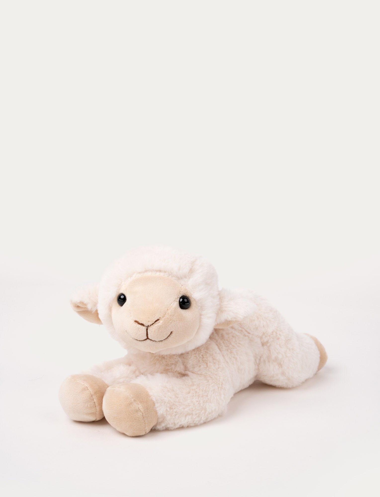  Image of Soft plush lamb with cream-colored fur, black bead eyes, and a stitched smile, lying down.