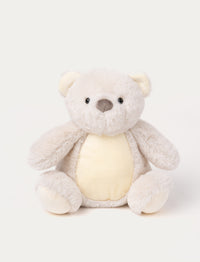 A light beige teddy bear with light yellow details on its stomach and paws, glowing in the dark.