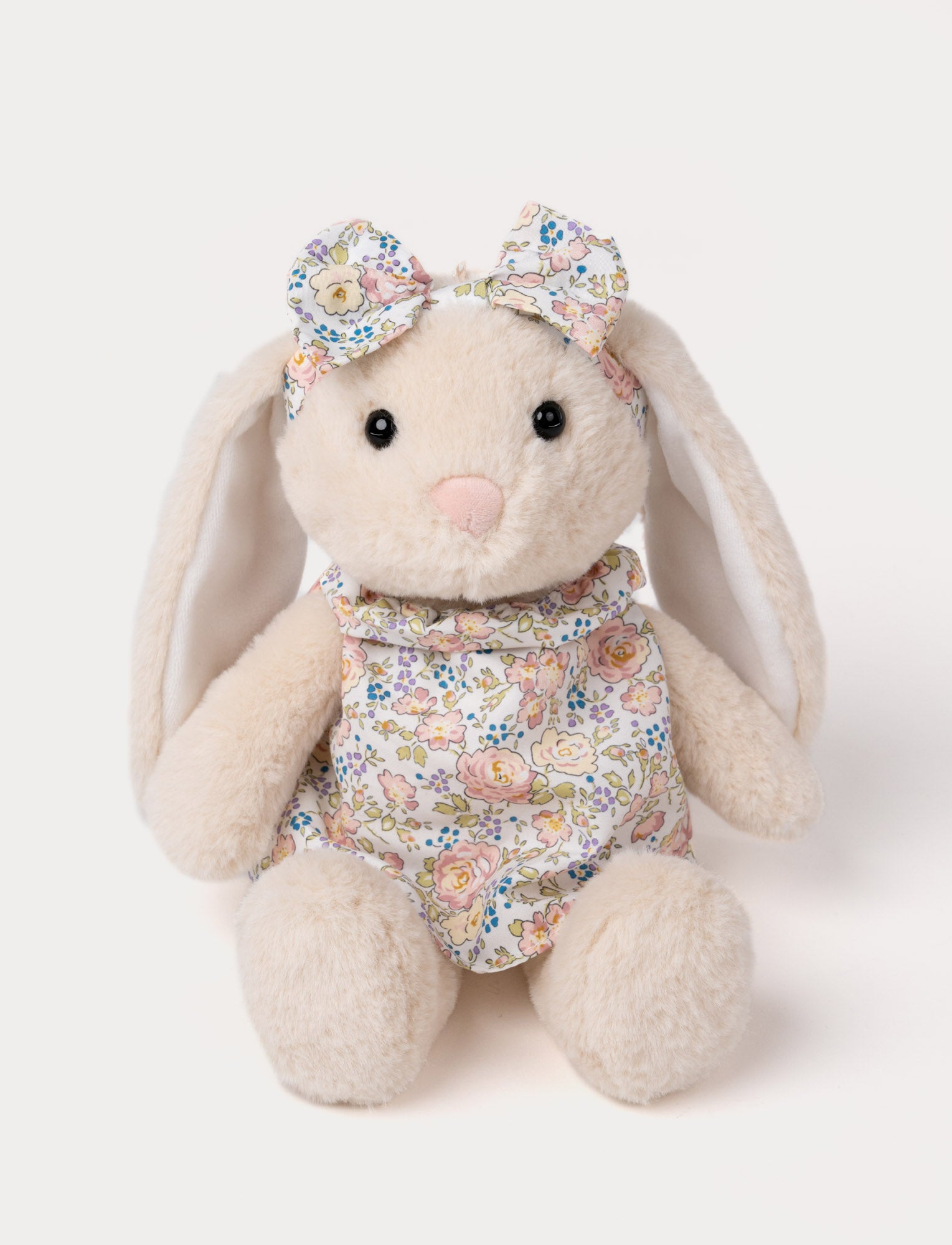  Image of Cream-colored plush bunny with floppy ears, wearing a floral dress and matching bow.