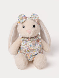 Cream-colored plush bunny with floppy ears, wearing a floral dress and matching bow.